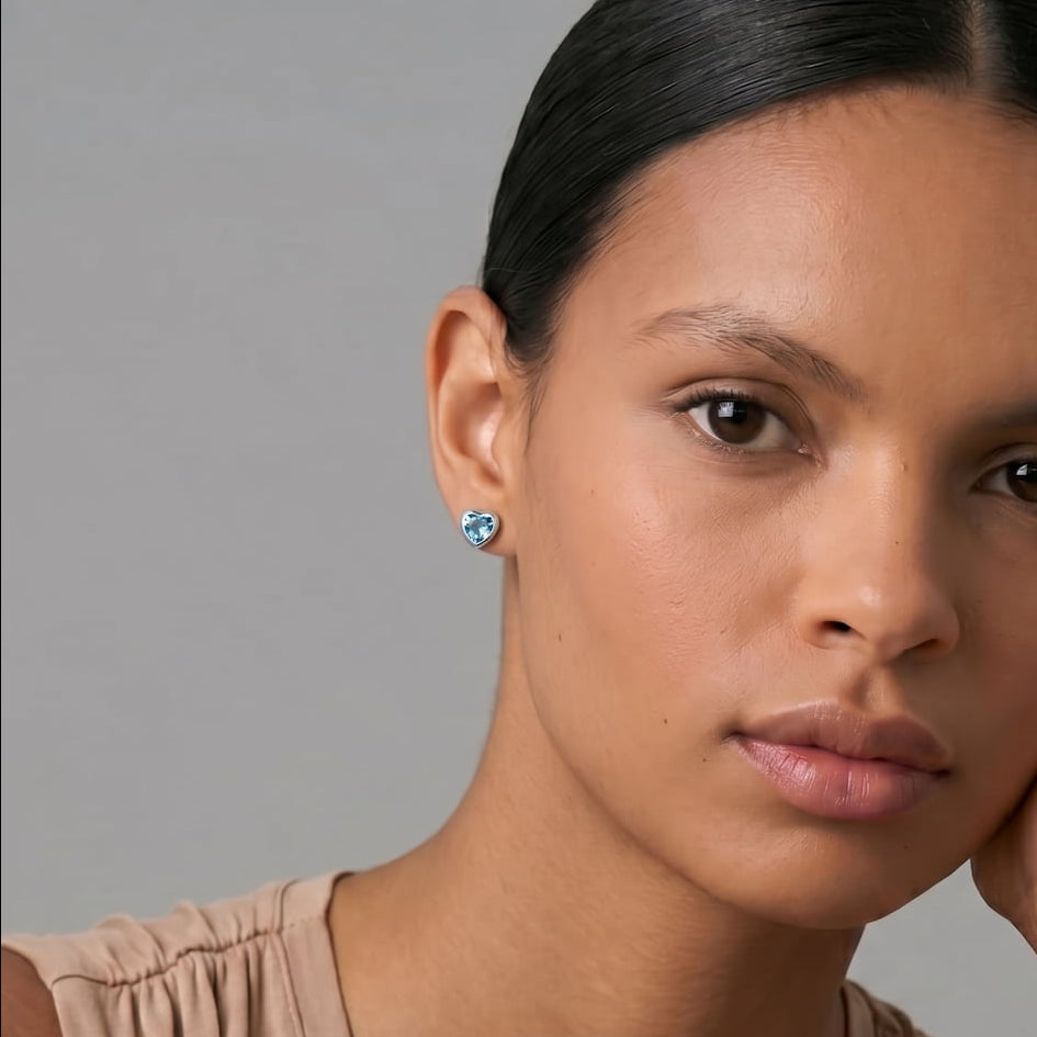 Close-up of a woman wearing a blue topaz heart-shaped earring