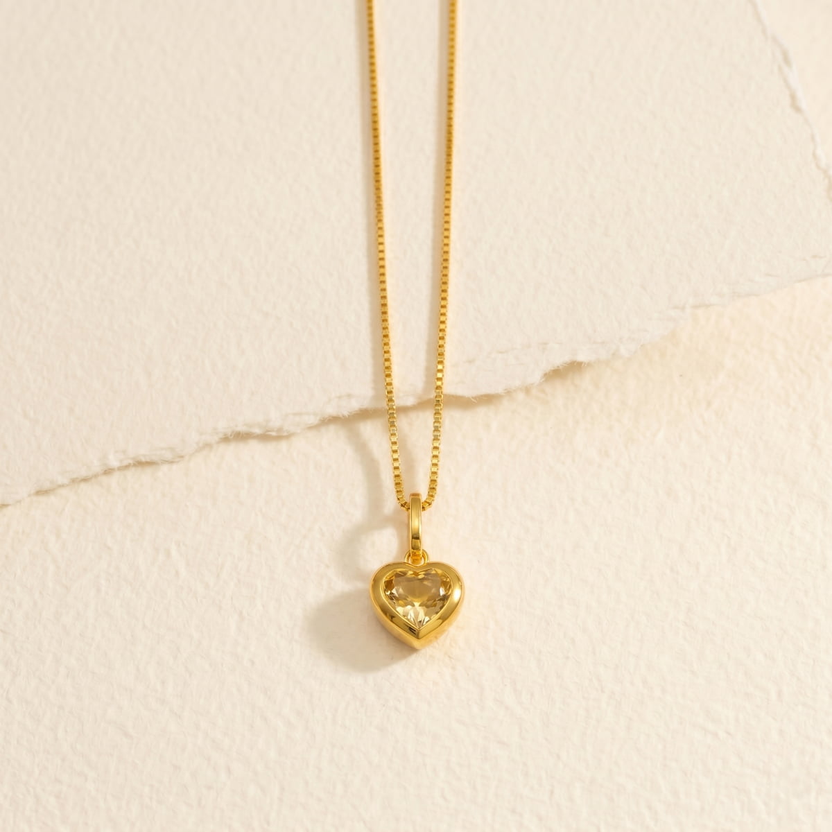 Gold vermeil heart-shaped citrene pendant on a beige paper background