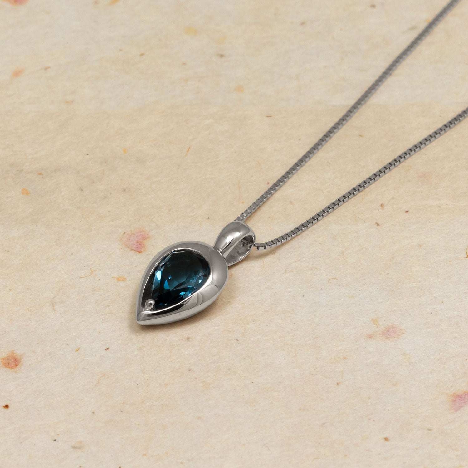 Sterling silver necklace featuring a teardrop pendant with a deep blue London Blue Topaz stone, showcasing a smooth, polished setting for an elegant, sculptural appearance.