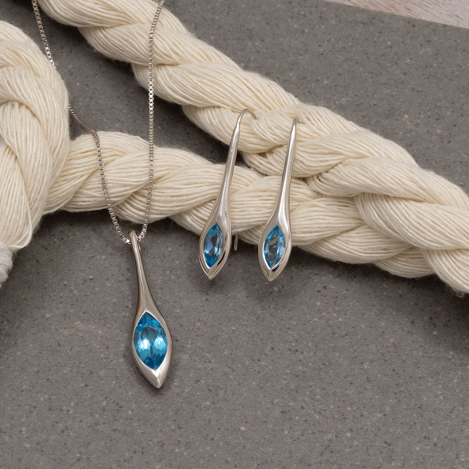 Pair of sterling silver drop earrings showcasing elongated marquise-shaped Swiss blue topaz stones set in sleek, polished silver for an elegant designer jewellery look.