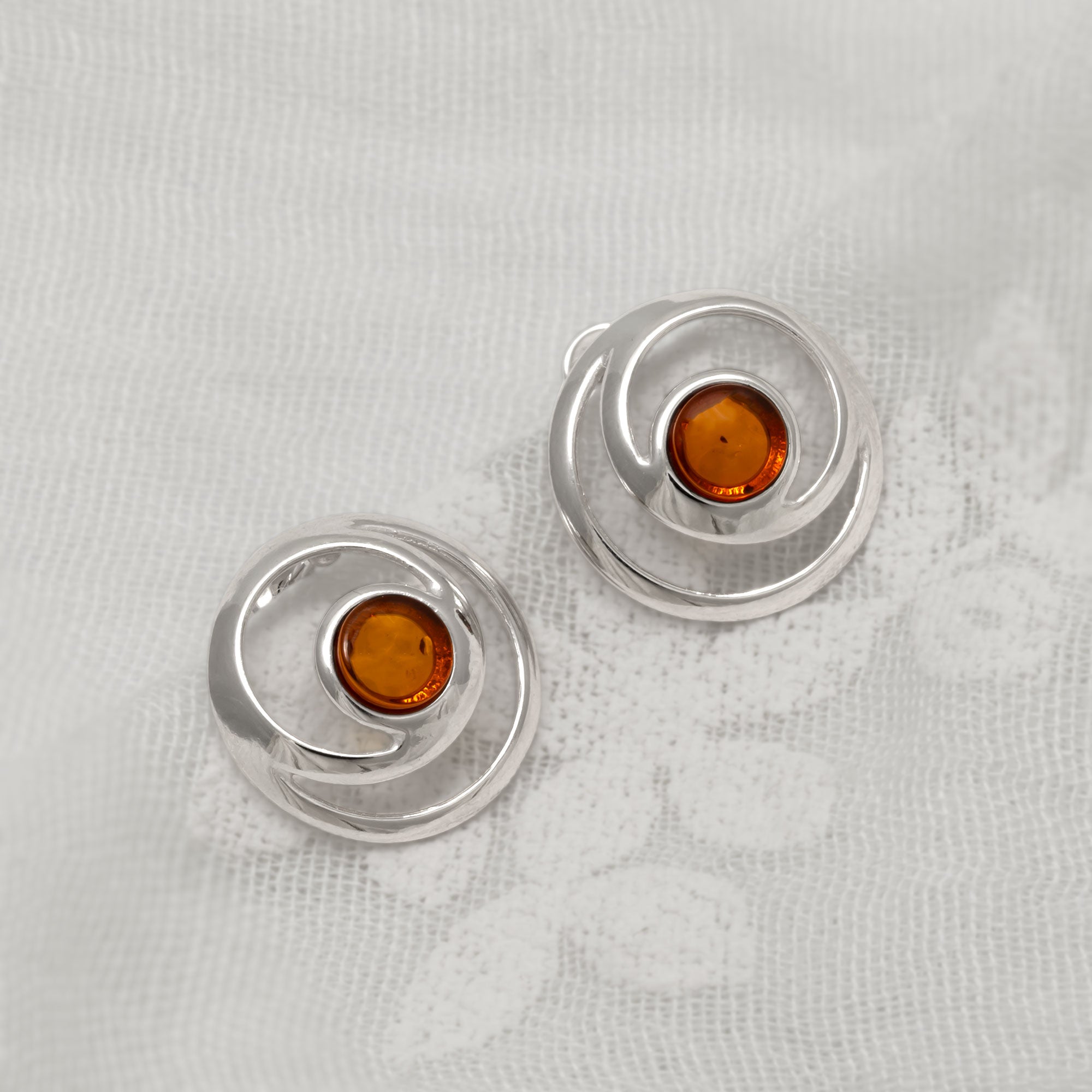 Silver earrings with amber stones on a light gray background