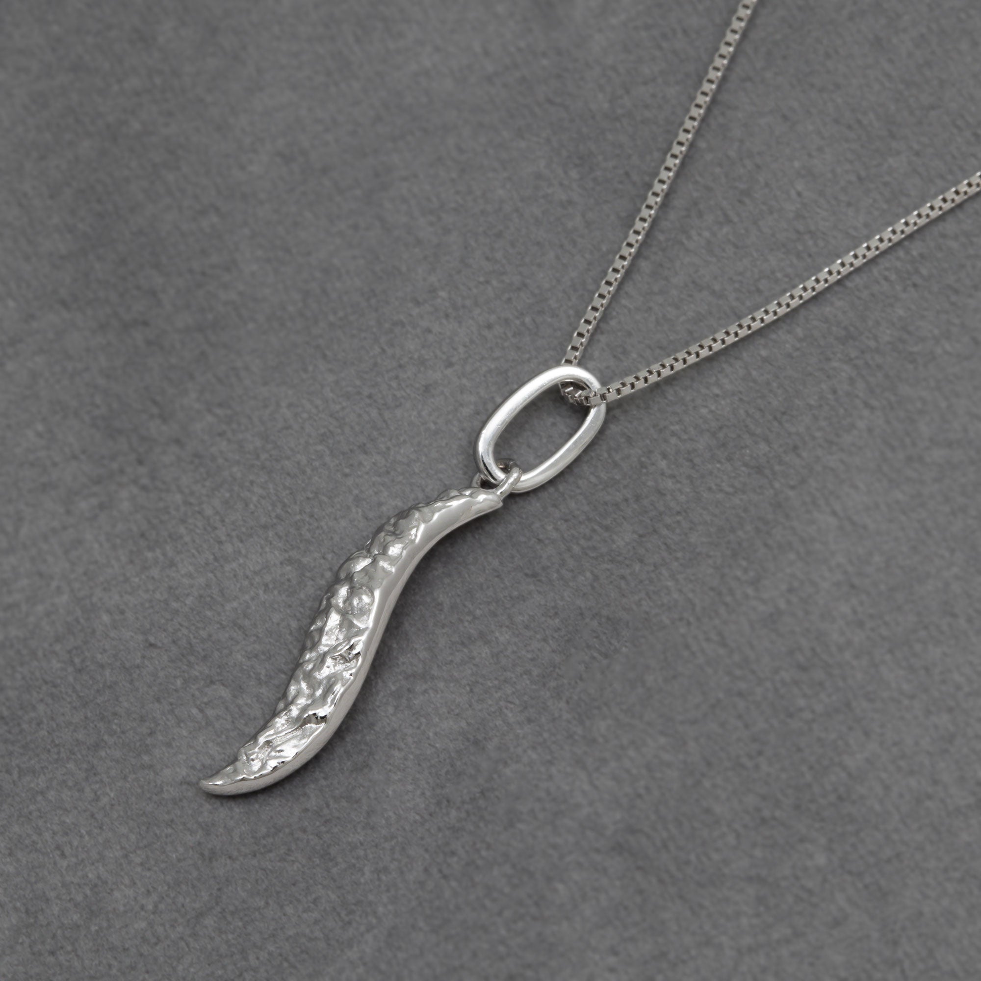 Silver textured leaf shape pendant necklace on a grey background