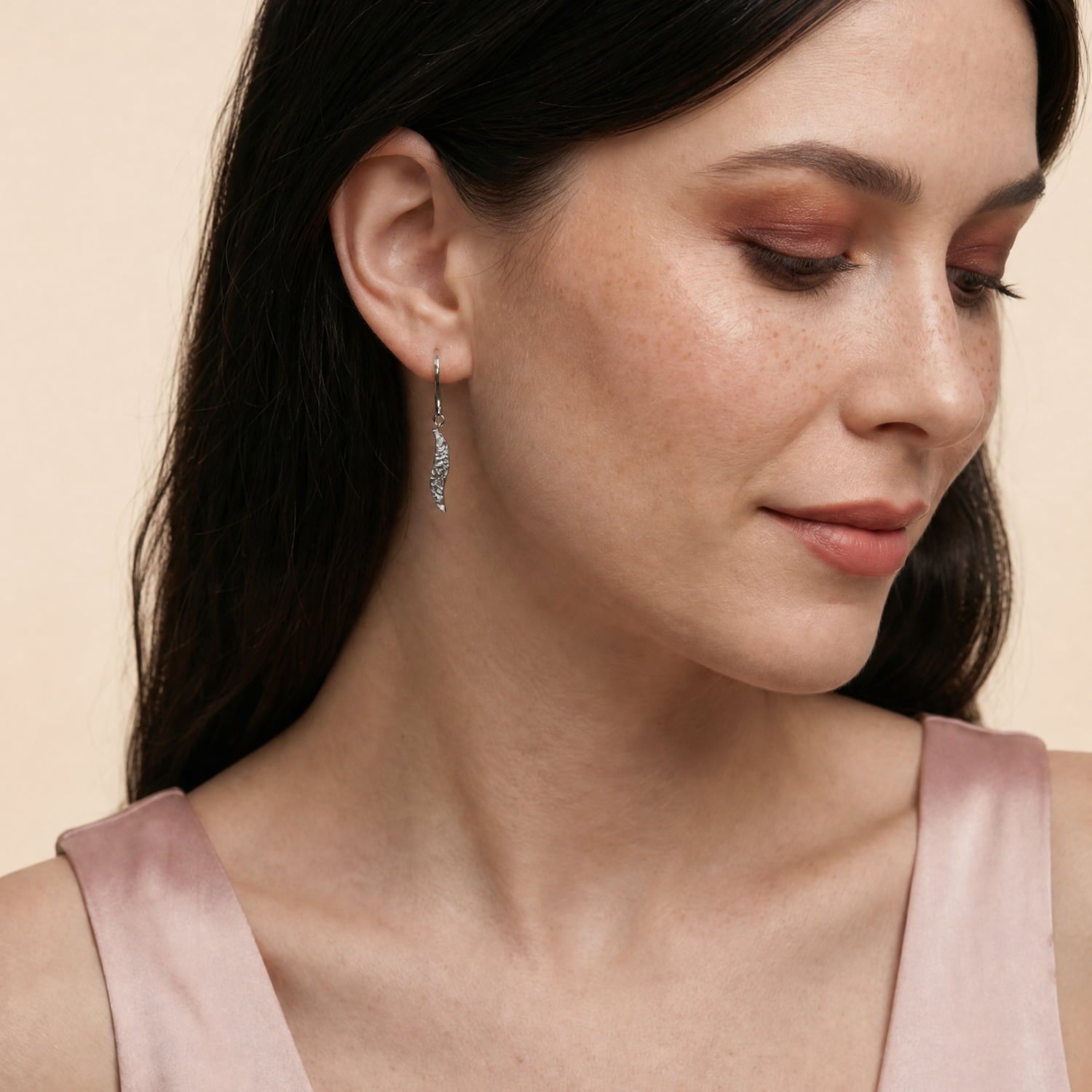 Model wears silver textured drop earrings with a wavy design
