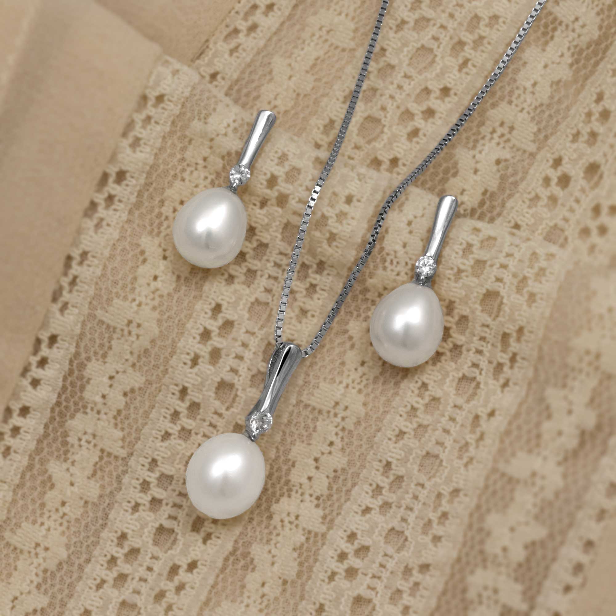 Set of sterling silver jewellery featuring large freshwater pearl teardrop pendants accented with sparkling cubic zirconia stones, displayed on delicate chains and matching earrings.