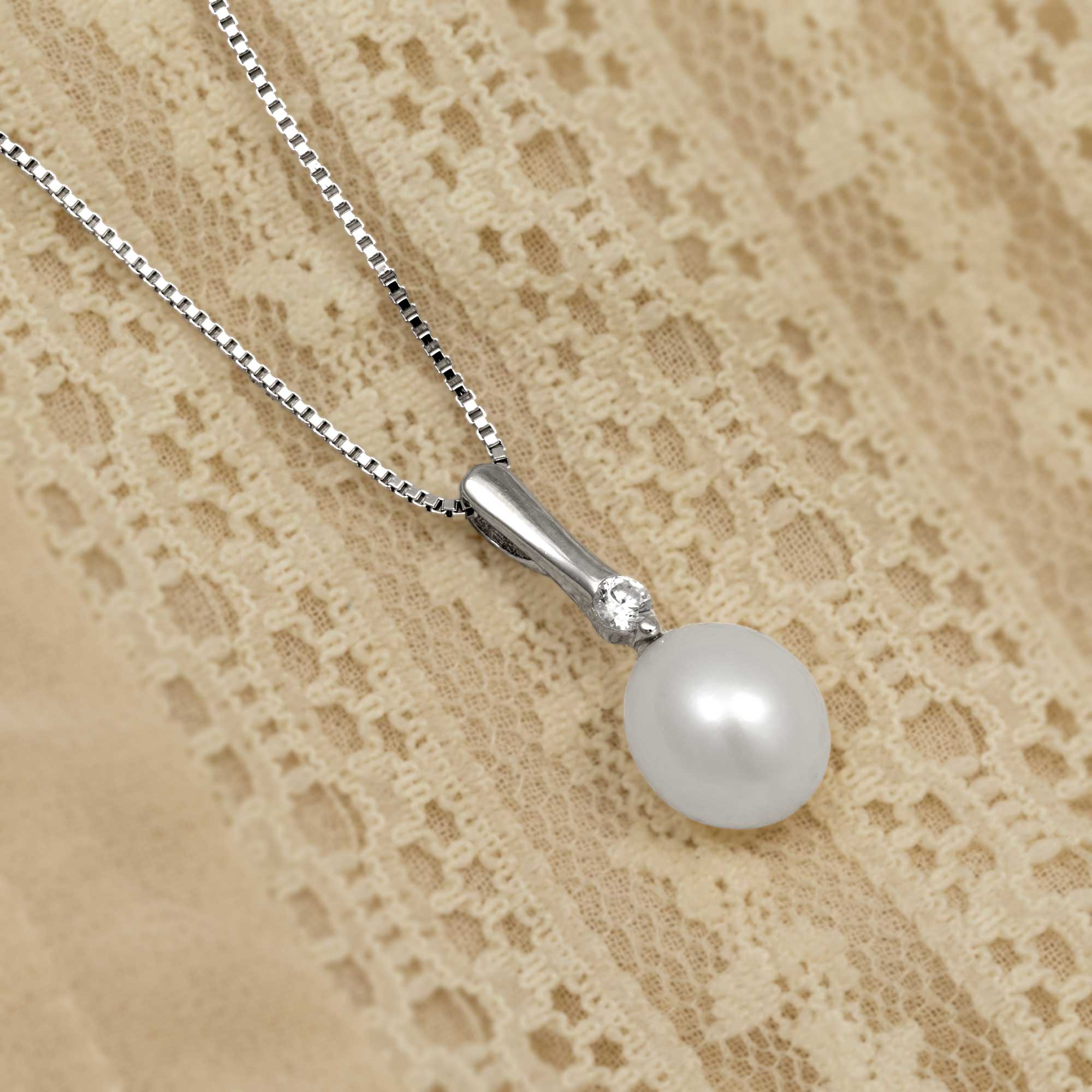 Pearl & sterling silver pendant with cubic zirconia on a cream background