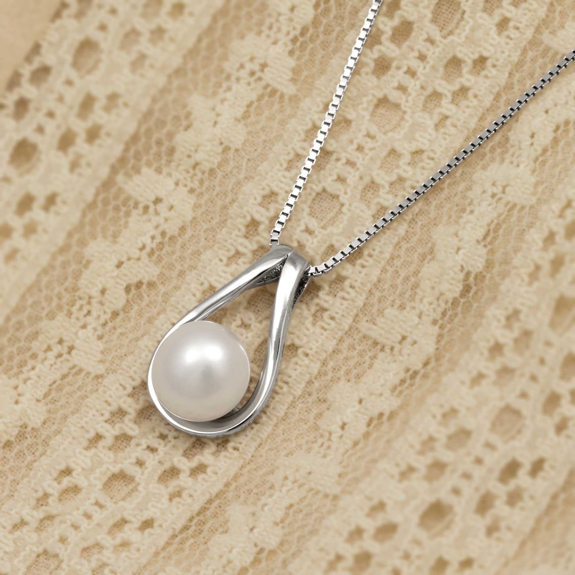 Teardrop-shaped silver and freshwater pendant on a cream background