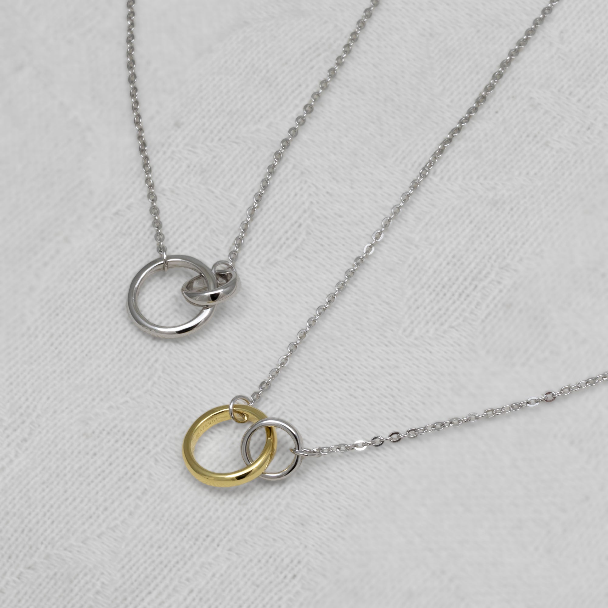 Two necklaces with interlocking rings on a light gray background