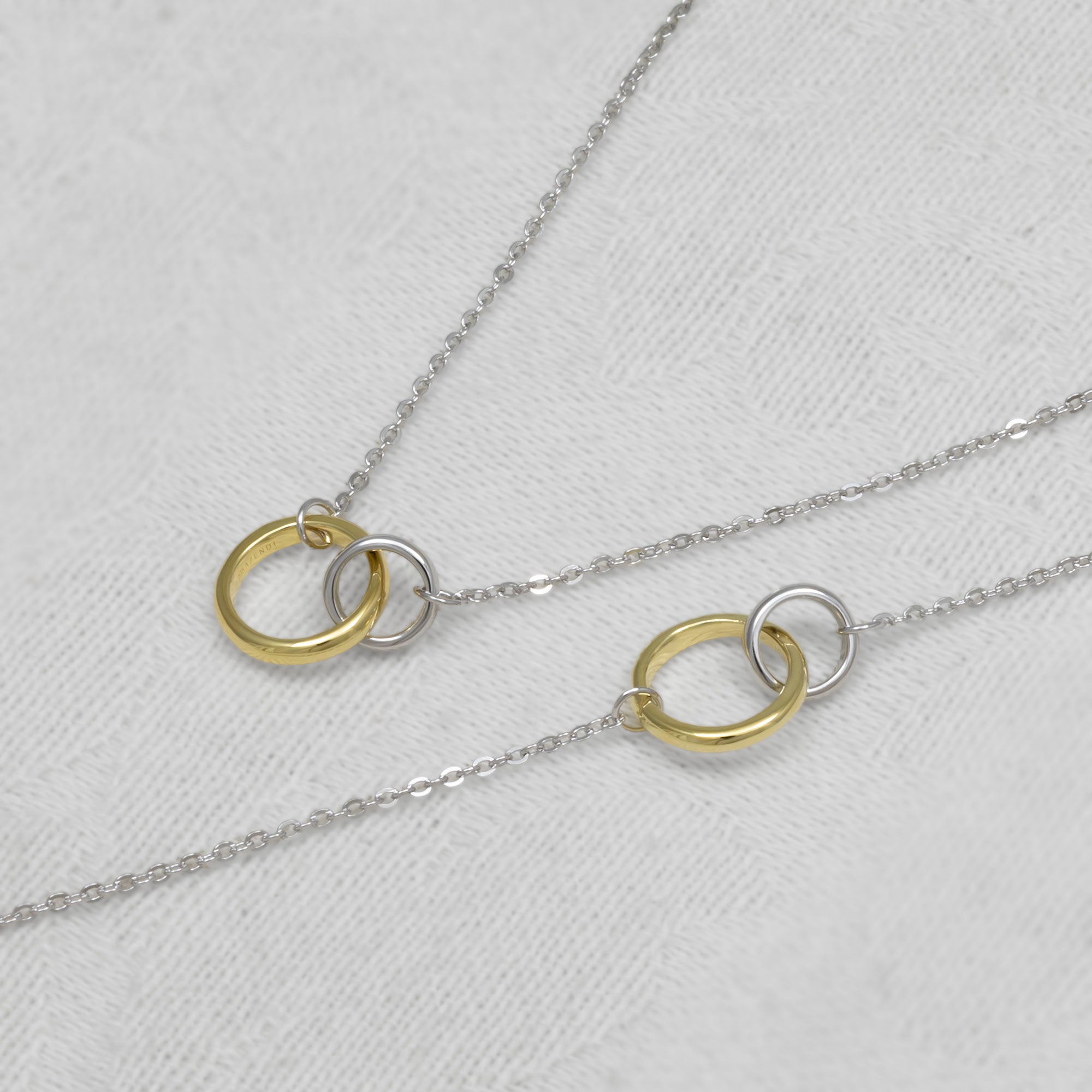 A necklace and bracelet set with interlocking rings on a light gray background