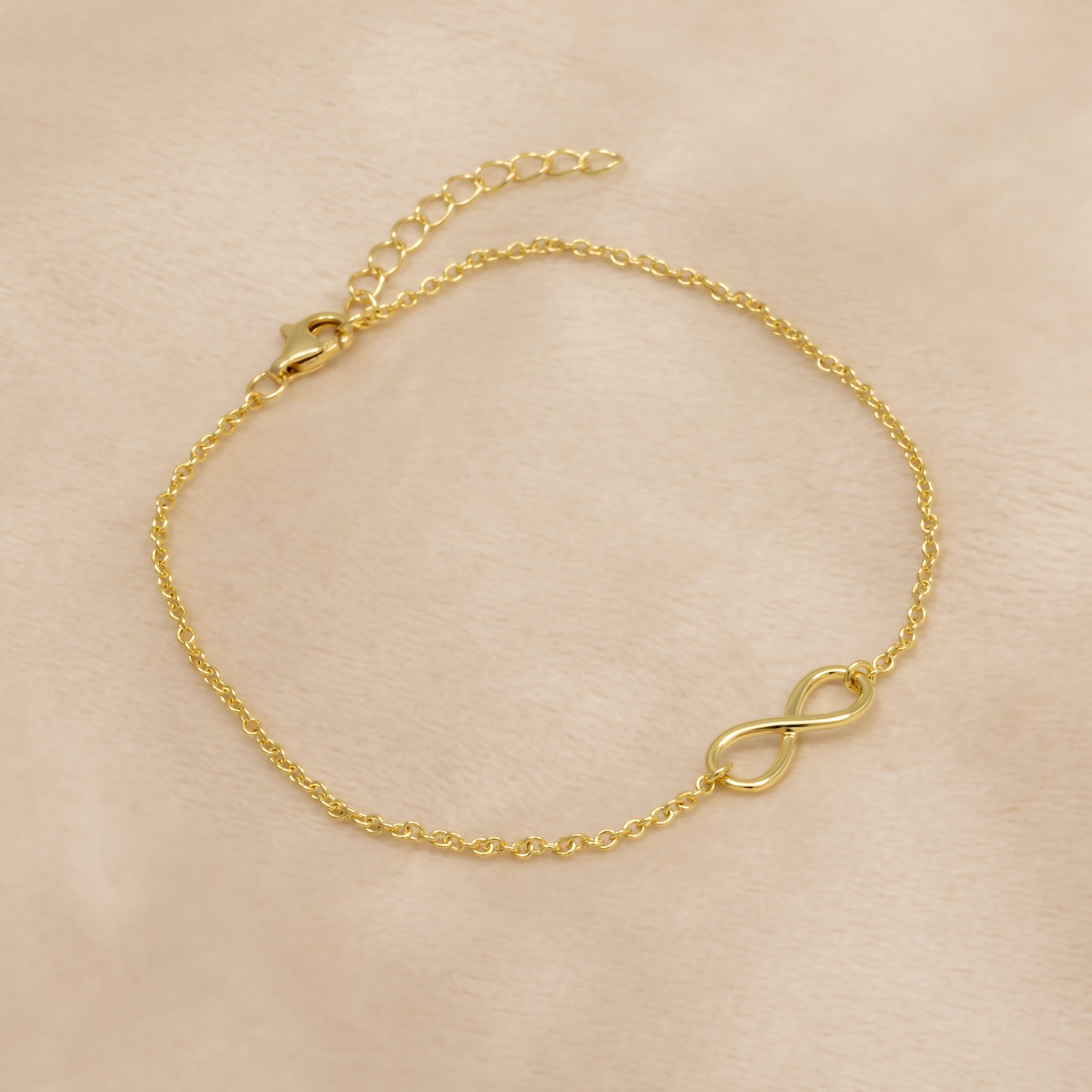 Gold vermeil bracelet with an infinity symbol on a beige background