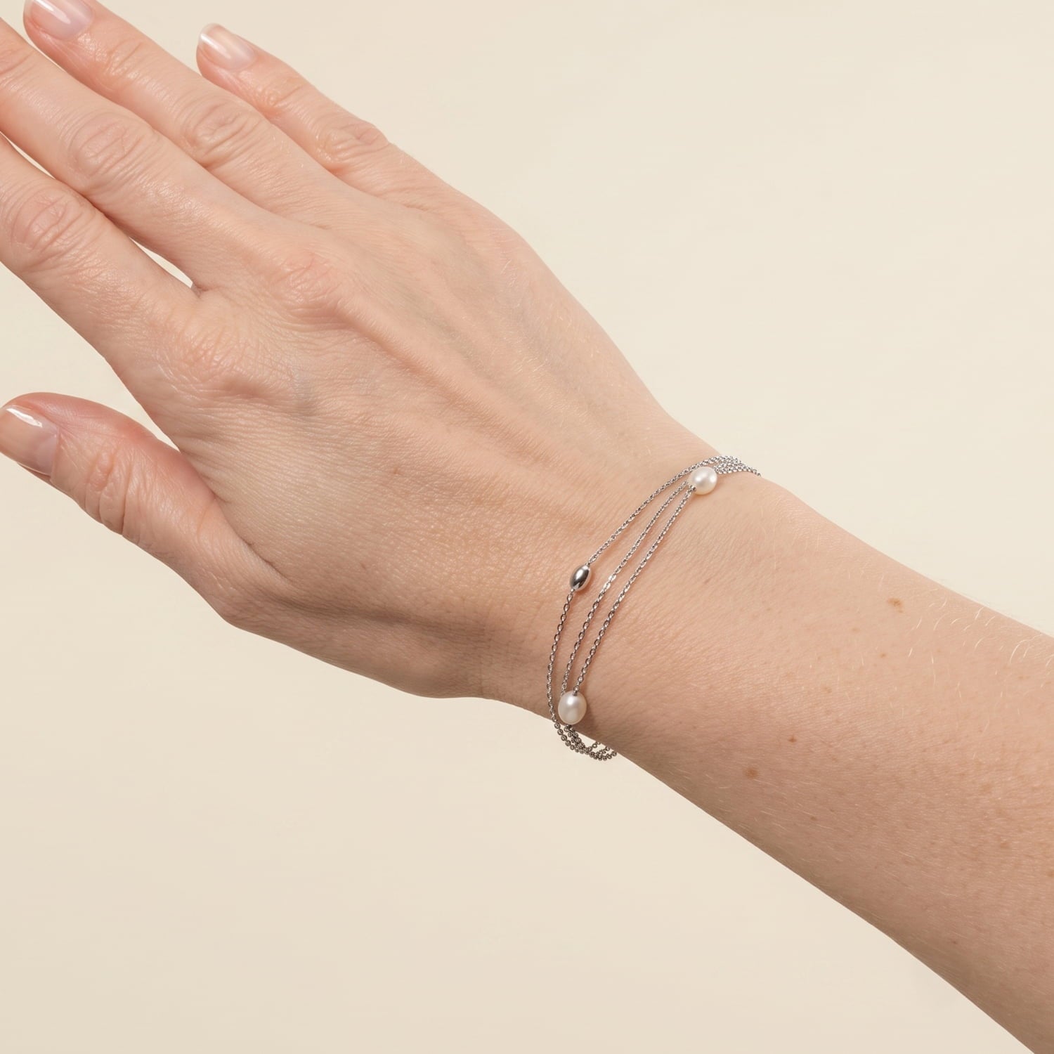 Model wears silver bracelet with multiple chains, freshwater pearls and silver beads.