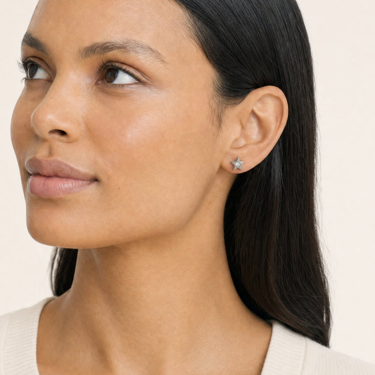 A model wears a pair of sterling silver star-shaped stud earrings, each featuring a round lab grown diamond in the center, set against a plain white background.