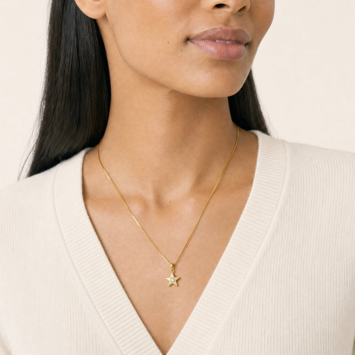 A model wears a gold vermeil star pendant with a lab grown diamond in the center, suspended from a gold vermeil box chain.