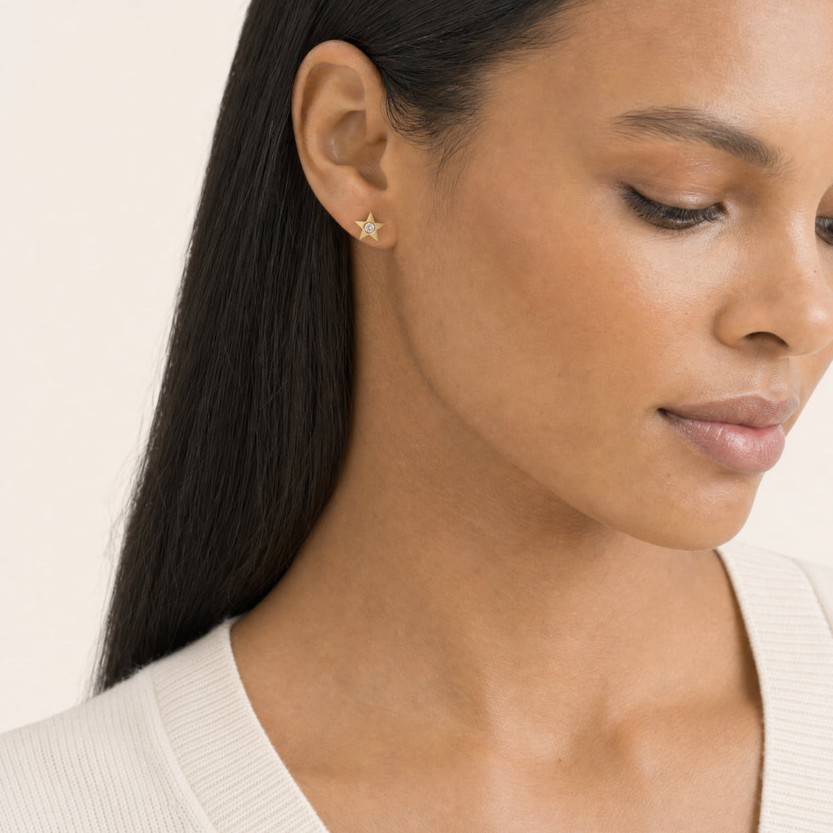Model wears a pair of gold vermeil star-shaped stud earrings, each featuring a round lab grown diamond in the center.