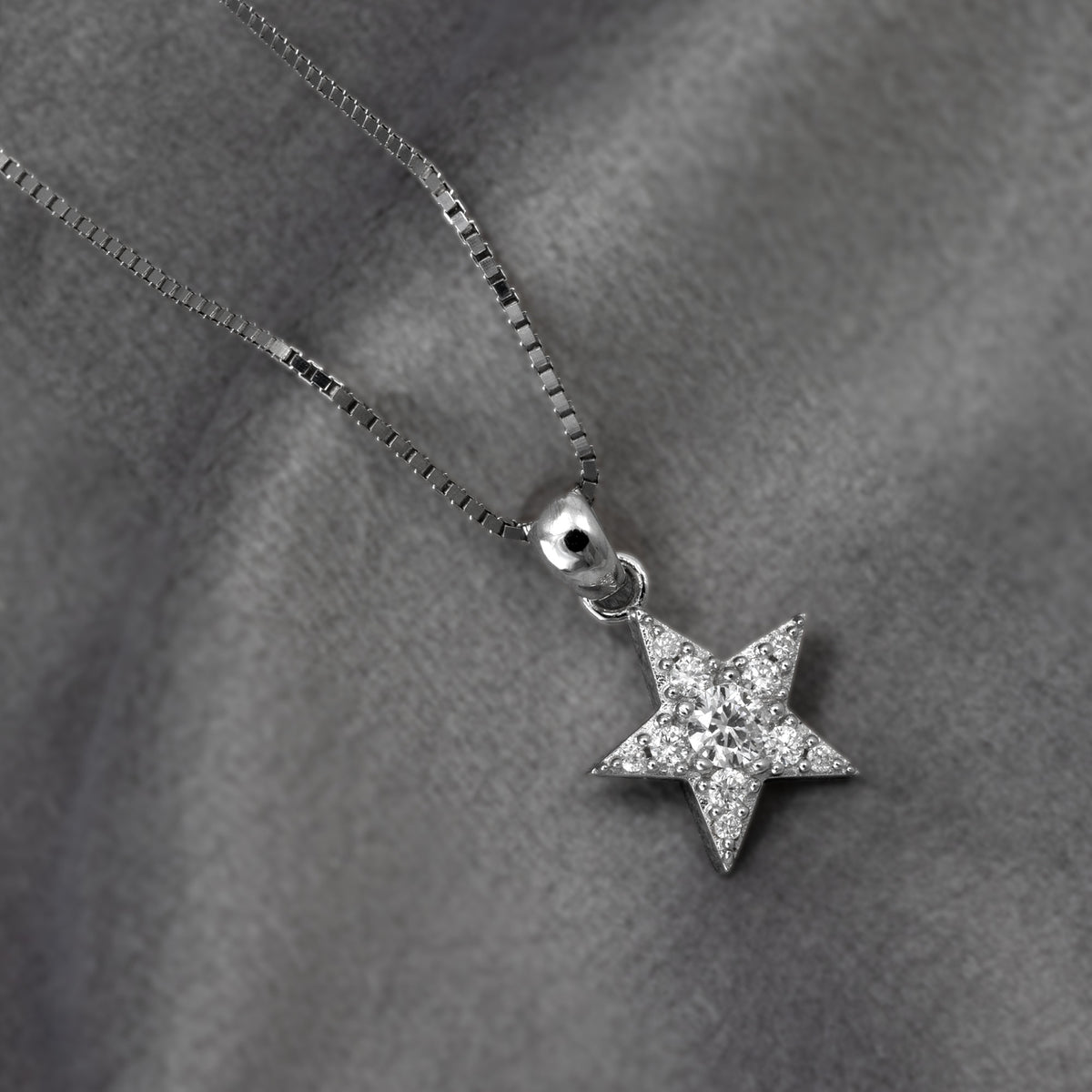 A silver star pendant necklace fully set with pavé lab grown diamonds, shown on a grey background.