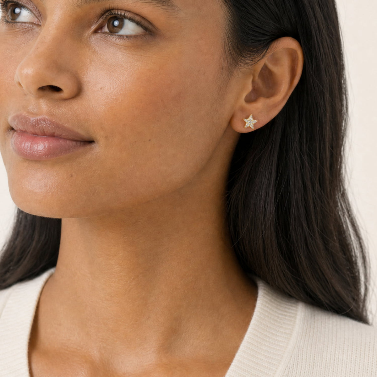 A close-up of a woman wearing a pair of gold vermeil star-shaped stud earrings fully set with pavé lab grown diamonds.