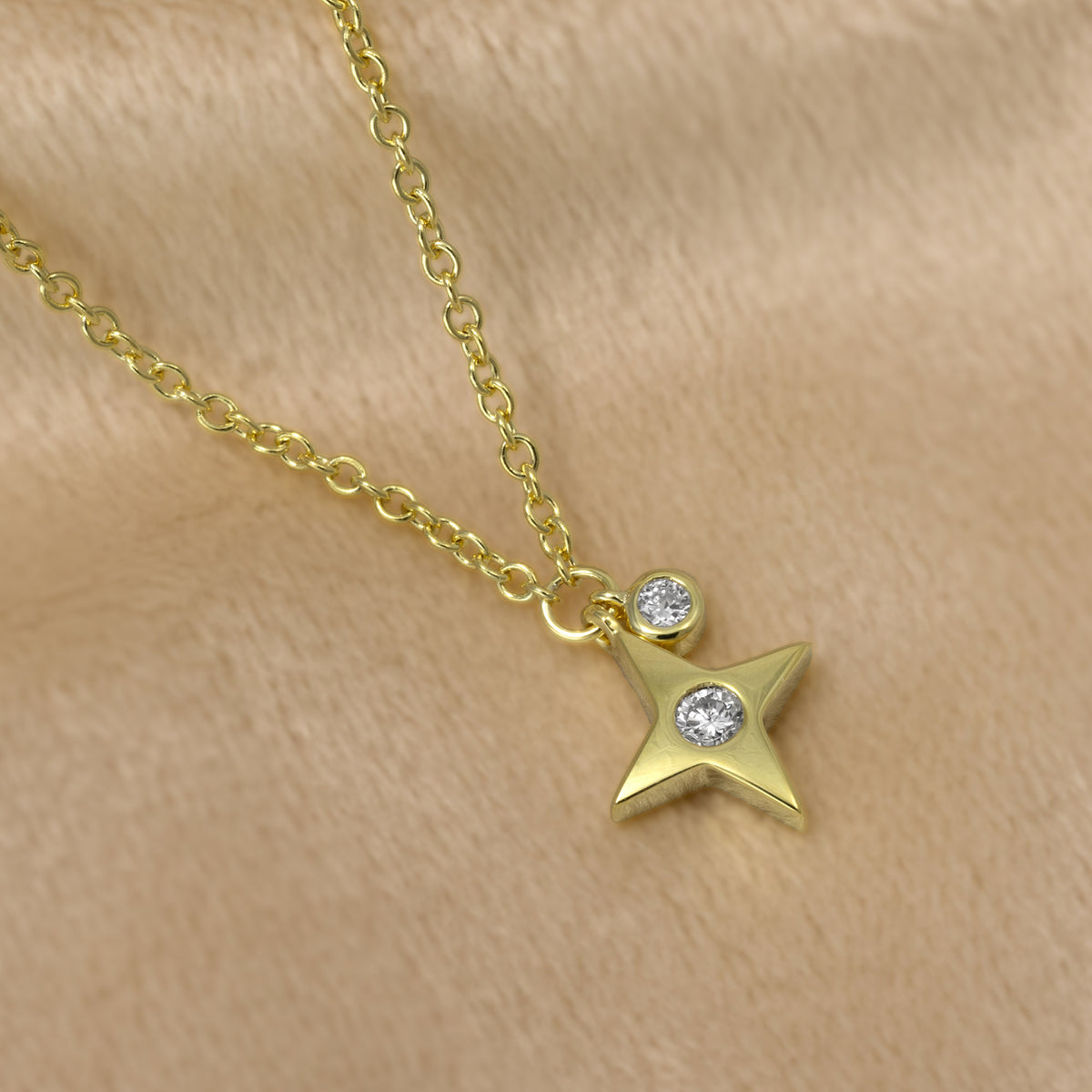 A gold vermeil necklace featuring a four-pointed star pendant with lab grown diamonds, displayed on a cream  background.