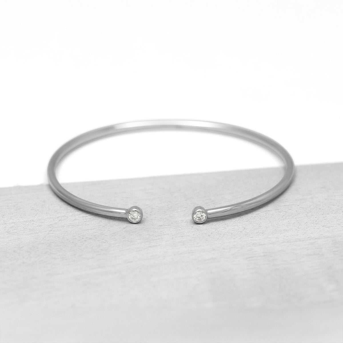 Silver bangle with lab grown diamonds on a white and grey background