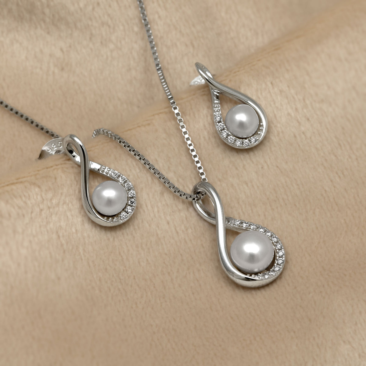 Pearl and lab grown diamond necklace and earrings set on a beige surface
