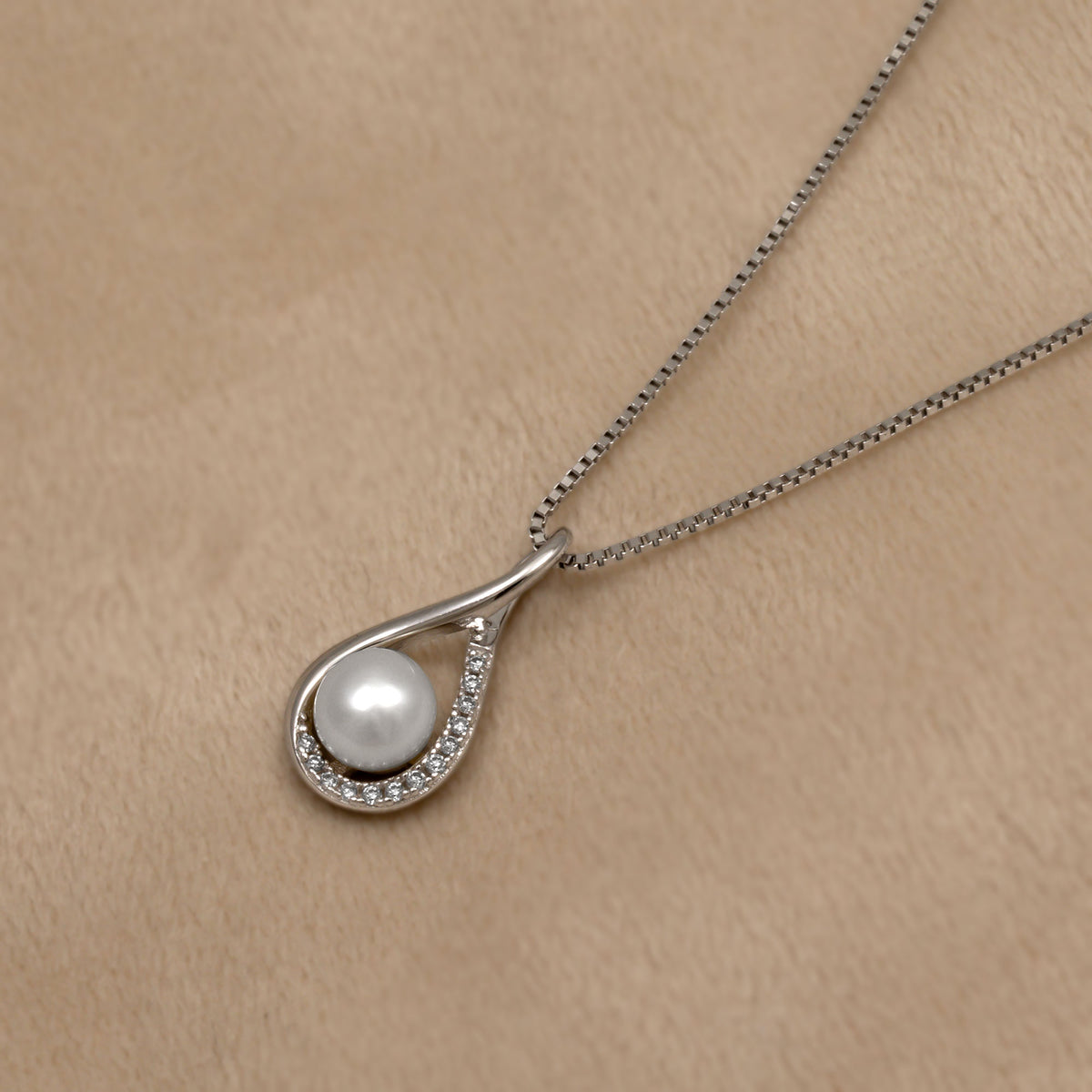 Pearl and lab grown diamond pendant necklace on a beige background