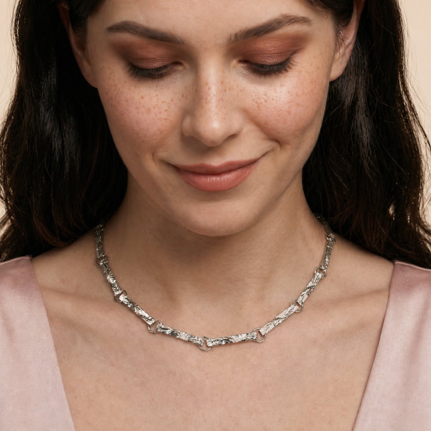 Model wears sterling silver necklace featuring elongated textured bar links connected by polished round rings.