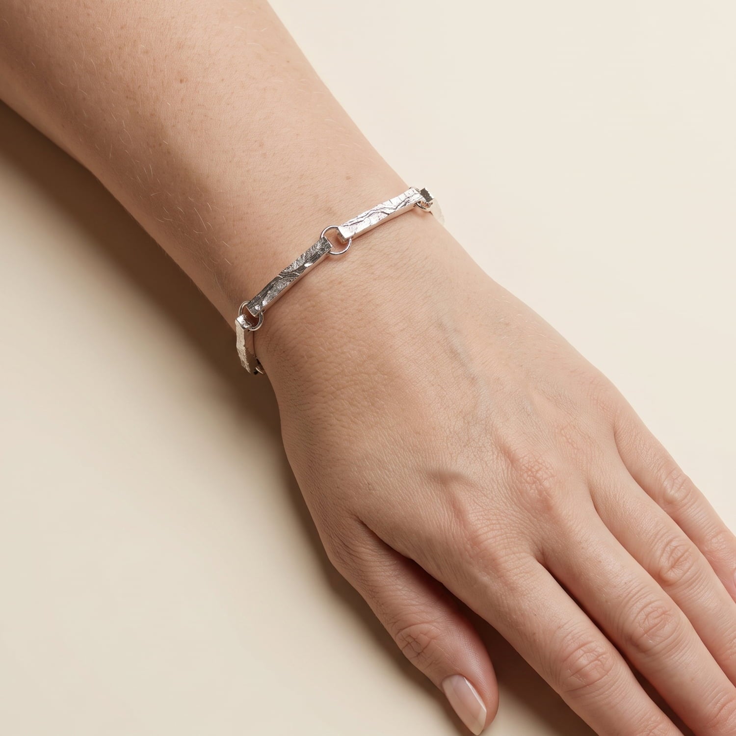 Model wears sterling silver link bracelet featuring elongated, textured bar-shaped links connected by small round rings.