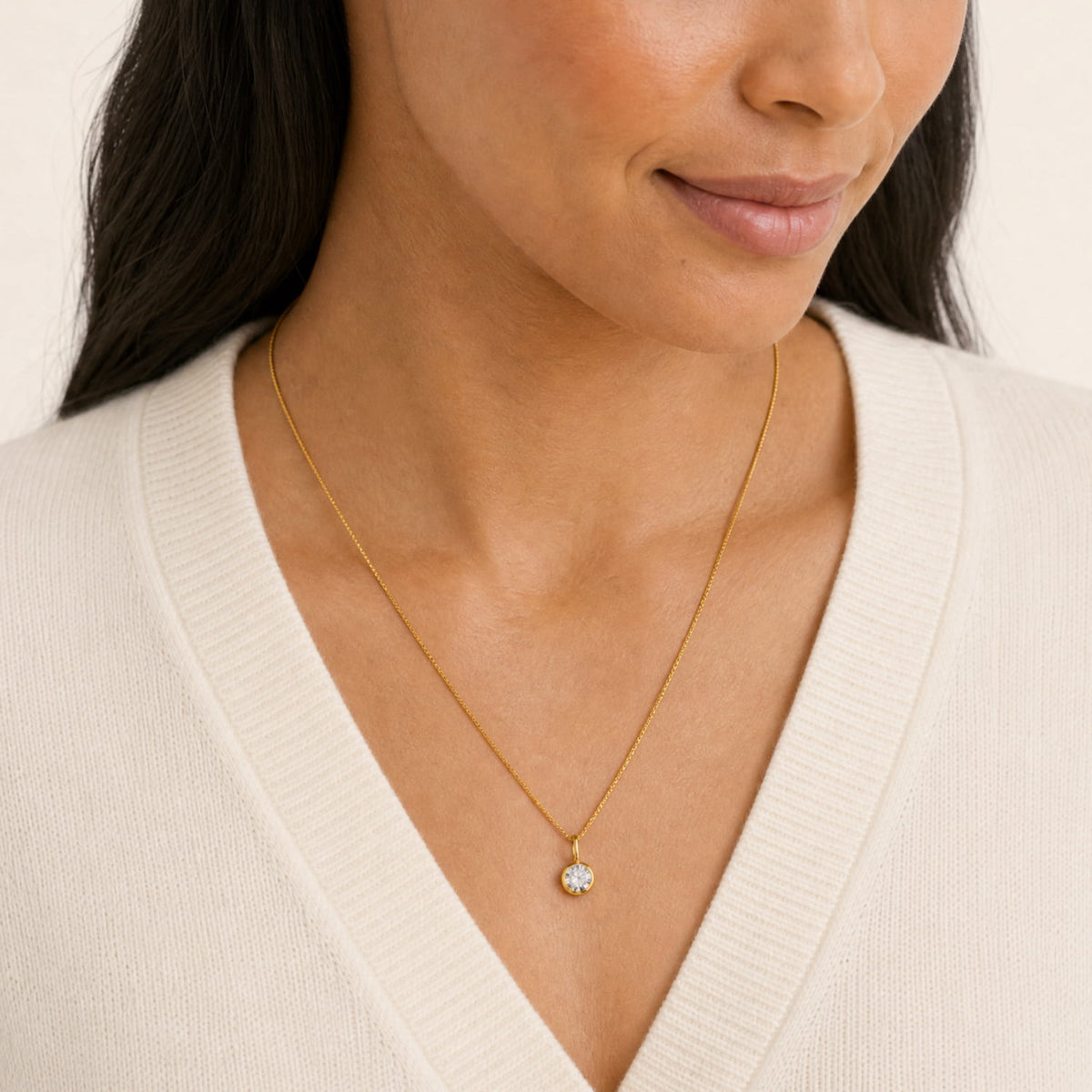 A woman wears a yellow gold vermeil box chain necklace with a round bezel-set 1/2 carat lab diamond pendant.