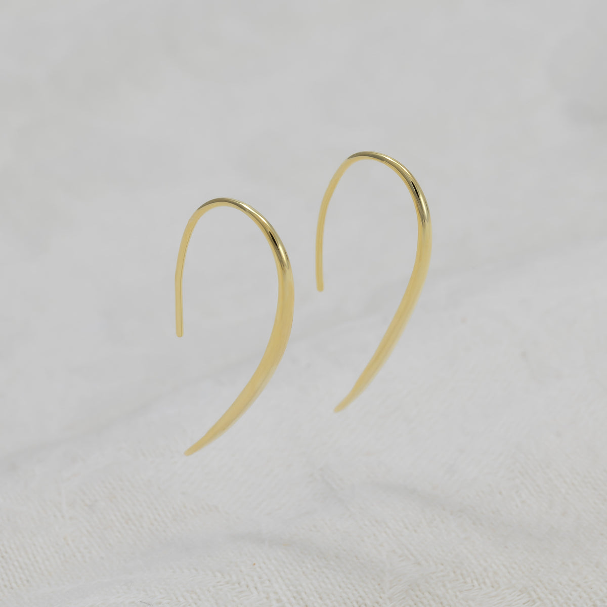 A pair of gold vermeil hook earrings with a polished finish.