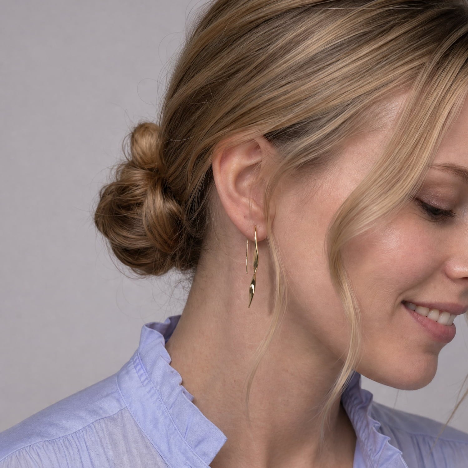 Model wears a pair of gold vermeil drop earrings with a twisted,  tapered design.