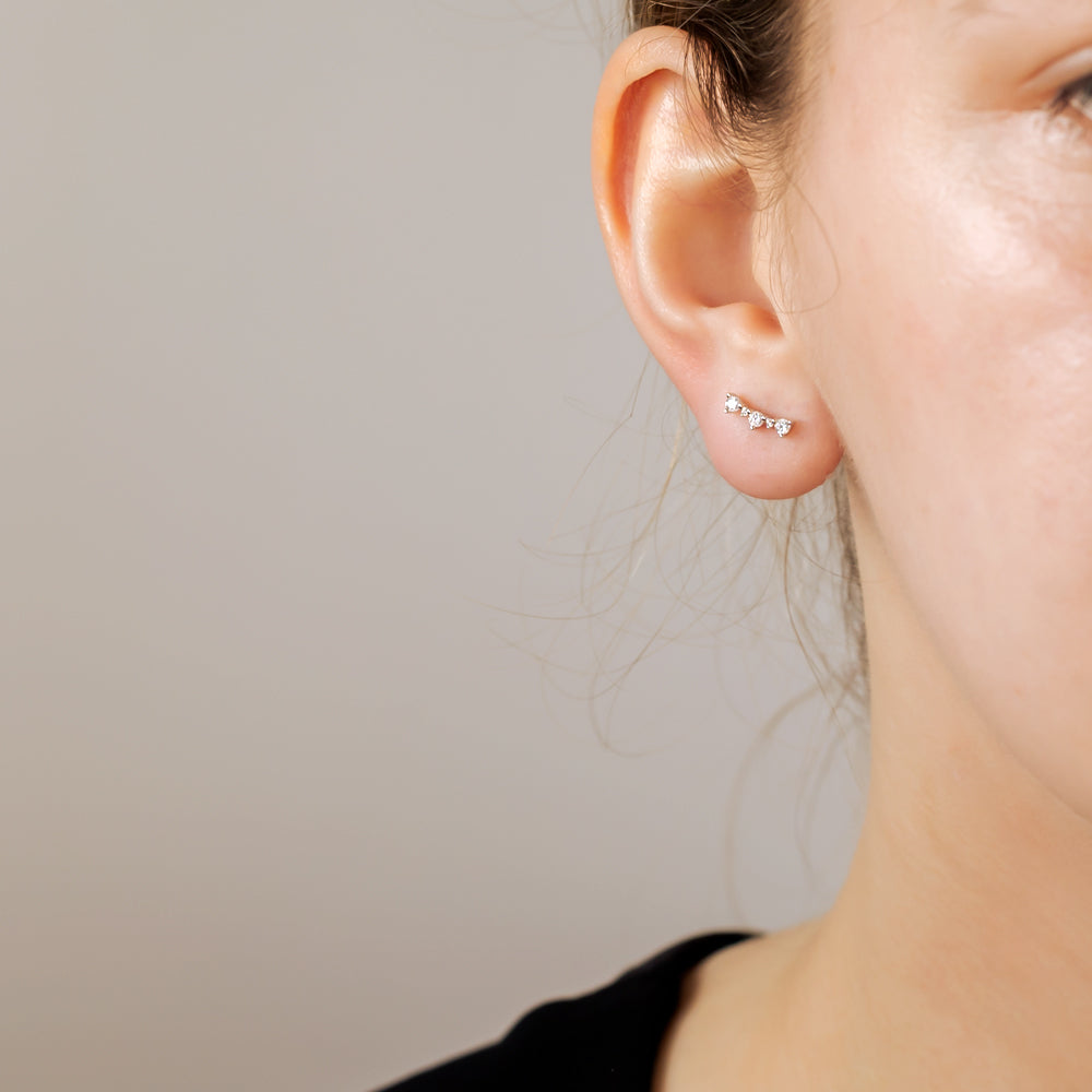 Delicate silver curved studs featuring a row of sparkling cubic zirconia stones, designed for a refined and contemporary look in sterling silver jewellery.