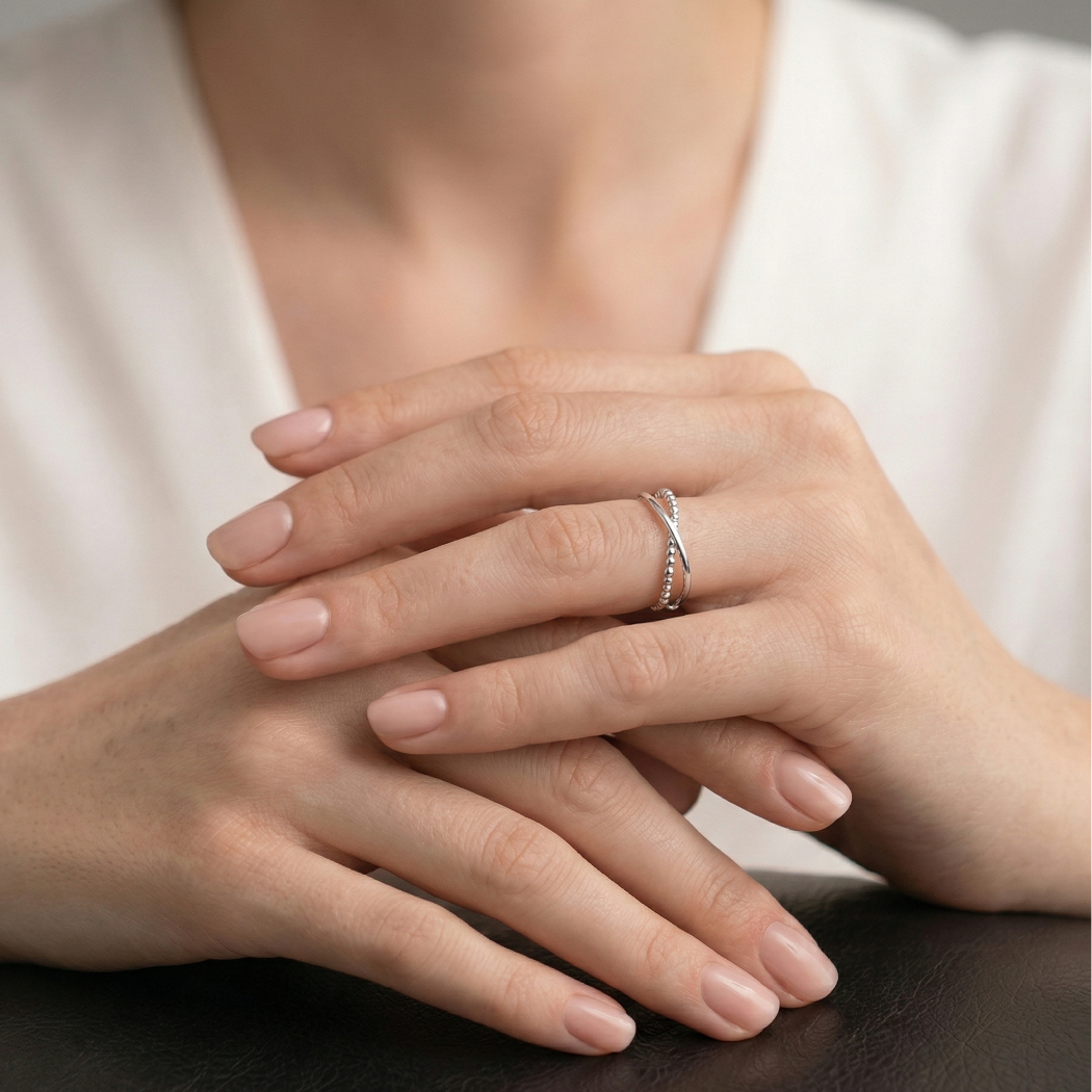 Sterling silver ring featuring two intertwined textured bands, showcasing a modern and sculptural design on a model’s finger for a refined jewellery statement.
