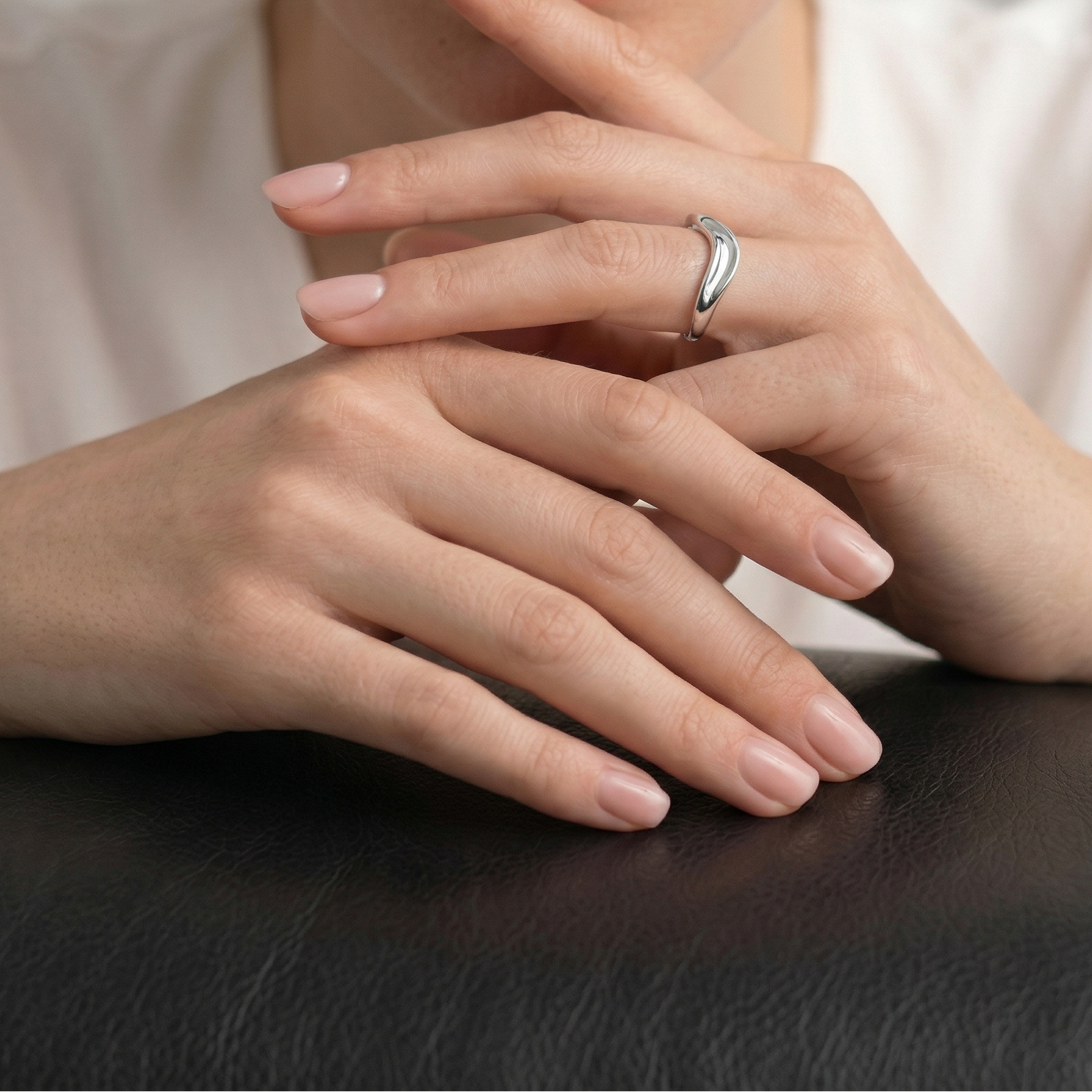 Polished sterling silver ring with a sculptural wave design, showcased on a hand against a neutral background, reflecting refined contemporary jewellery style.