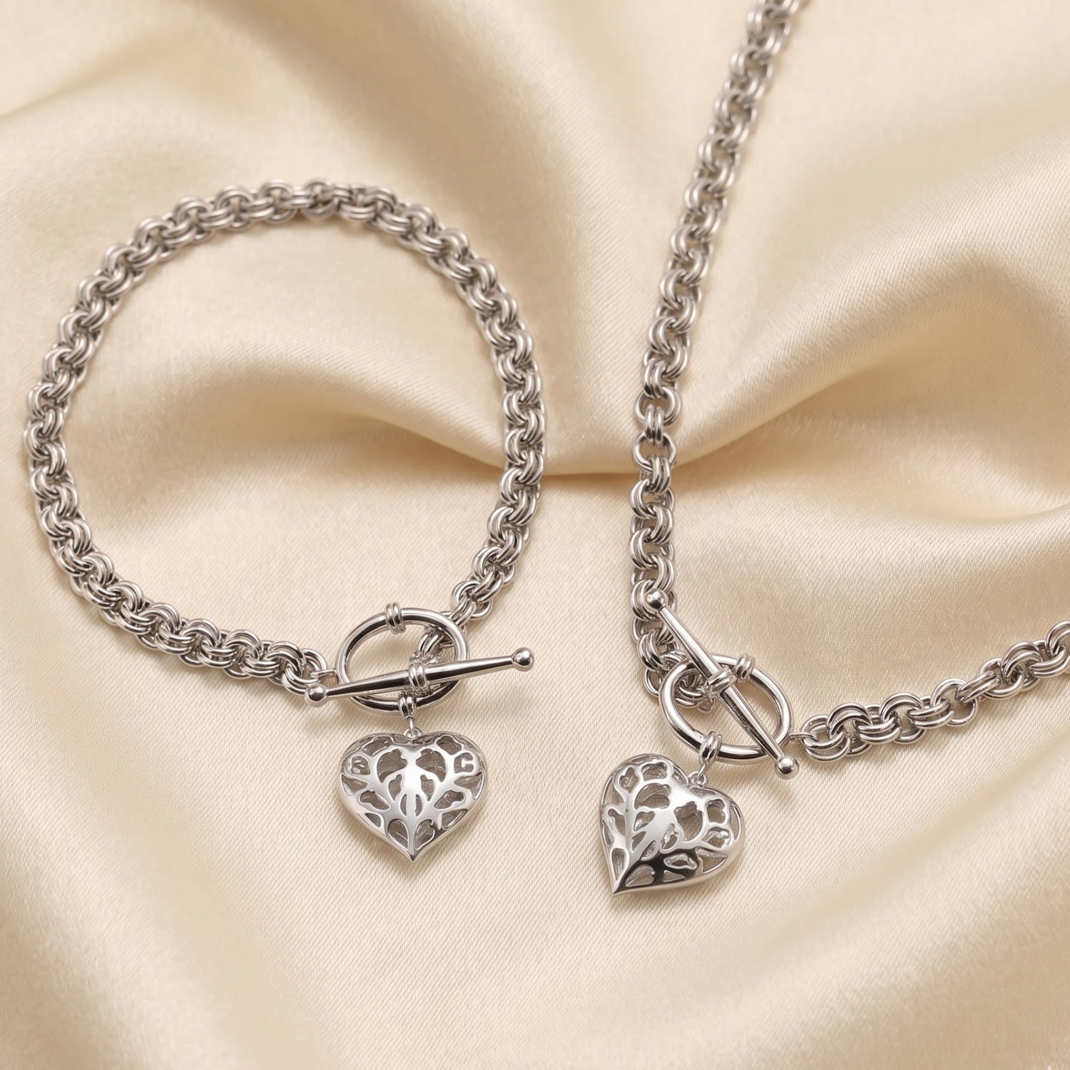 Sterling silver bracelet and necklace set featuring chunky sculptural chains and dangling openwork hearts with T-bar fastenings, crafted in fine silver jewellery design.
