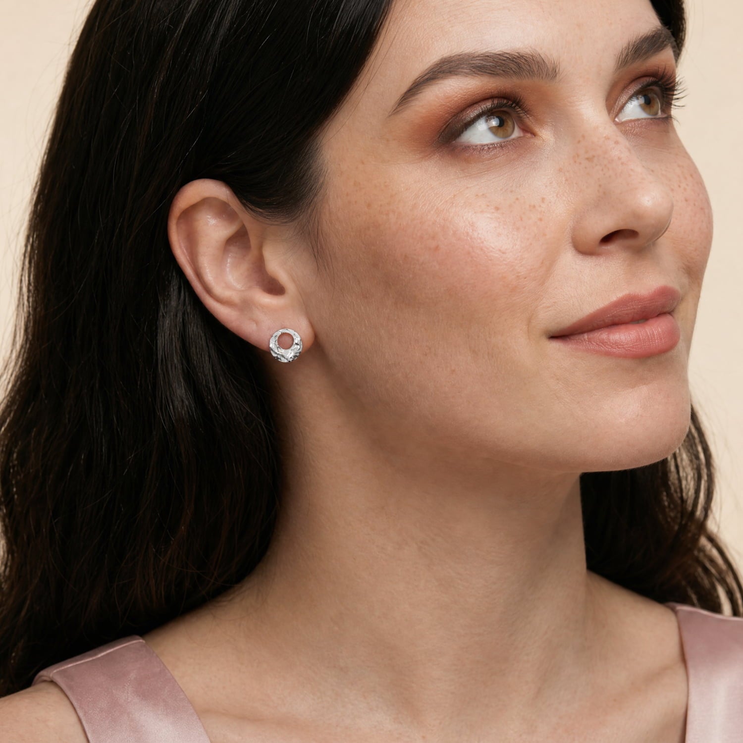 A model wears a pair of sterling silver stud earrings featuring textured circular discs with central cut-outs, showcasing a contemporary sculptural design in fine silver jewellery.
