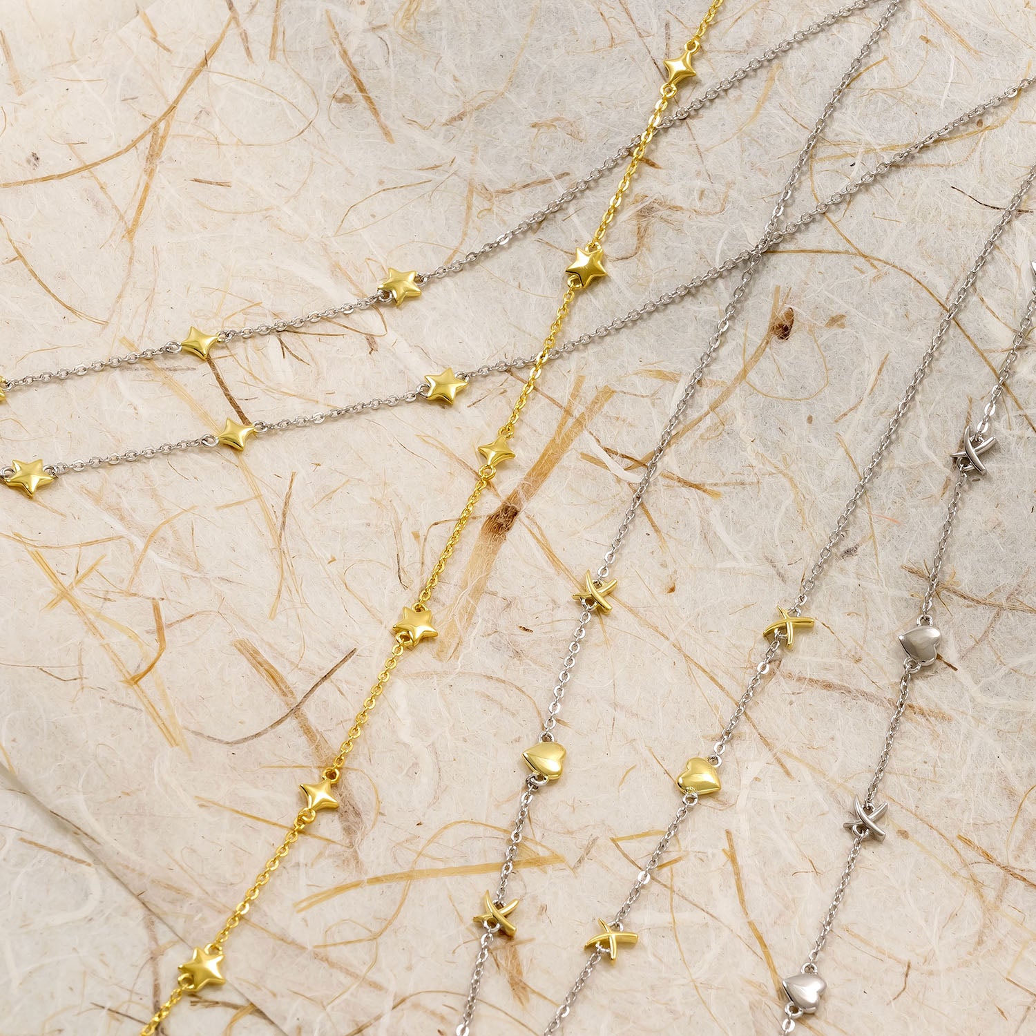 Delicate sterling silver and gold vermeil necklaces featuring small star, heart, and cross-shaped charms on fine chains, combining sculptural elegance with refined contemporary design.