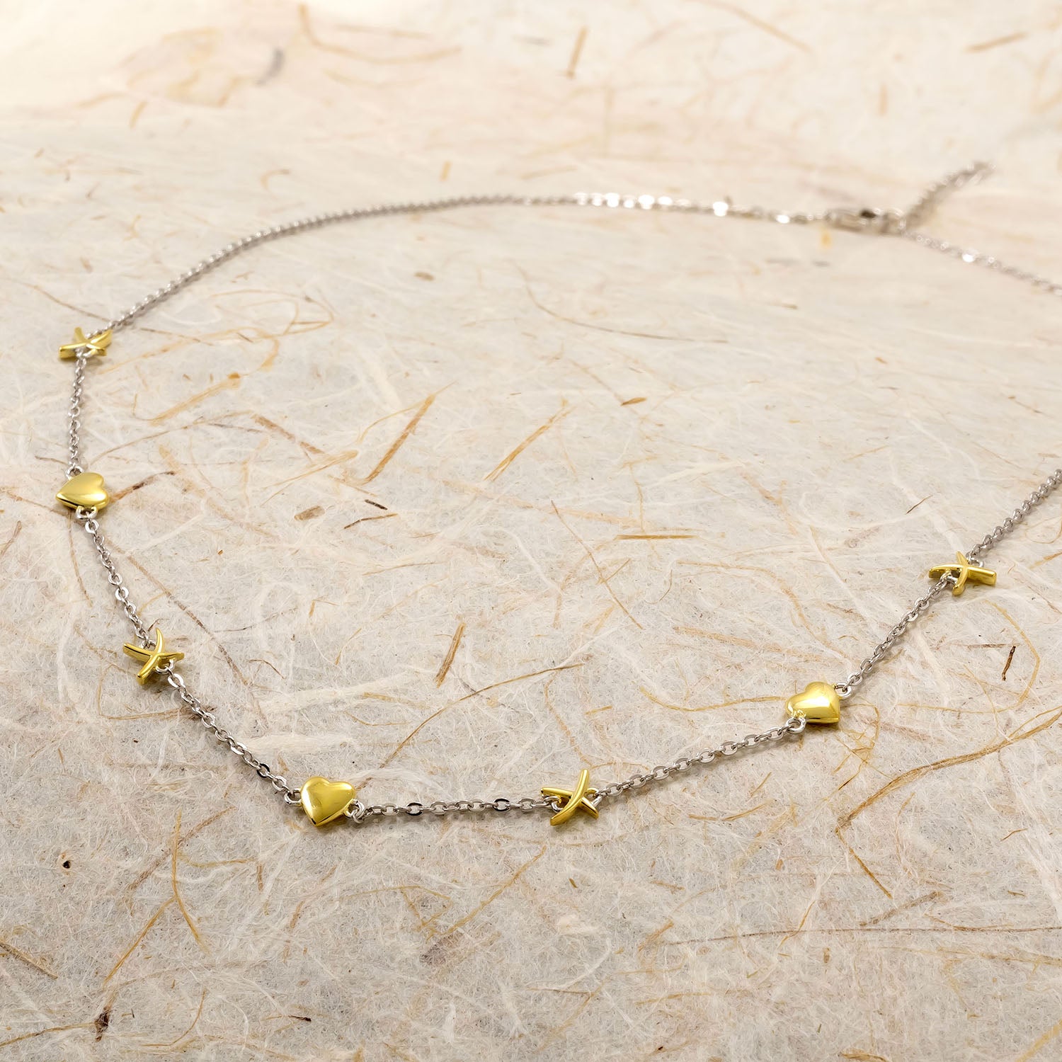 Sterling silver necklace featuring small sculptural hearts and kisses motifs in a polished gold vermeil finish, creating a delicate and contemporary design.