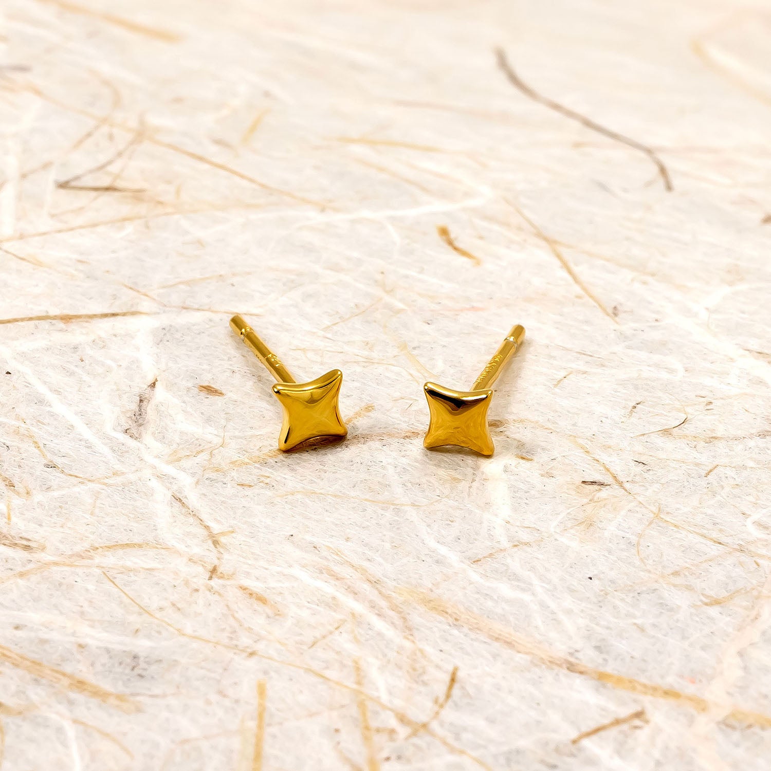 Pair of polished gold vermeil four-point star stud earrings, featuring a sleek and sculptural design crafted for refined contemporary elegance.