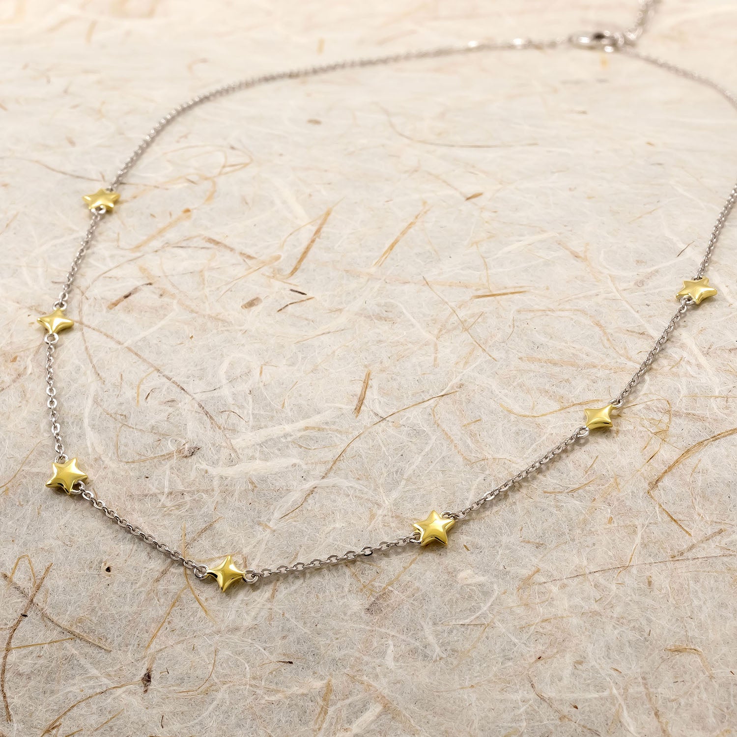 Delicate sterling silver necklace featuring small sculptural gold vermeil star-shaped accents evenly spaced along a fine chain, blending celestial charm with refined design.