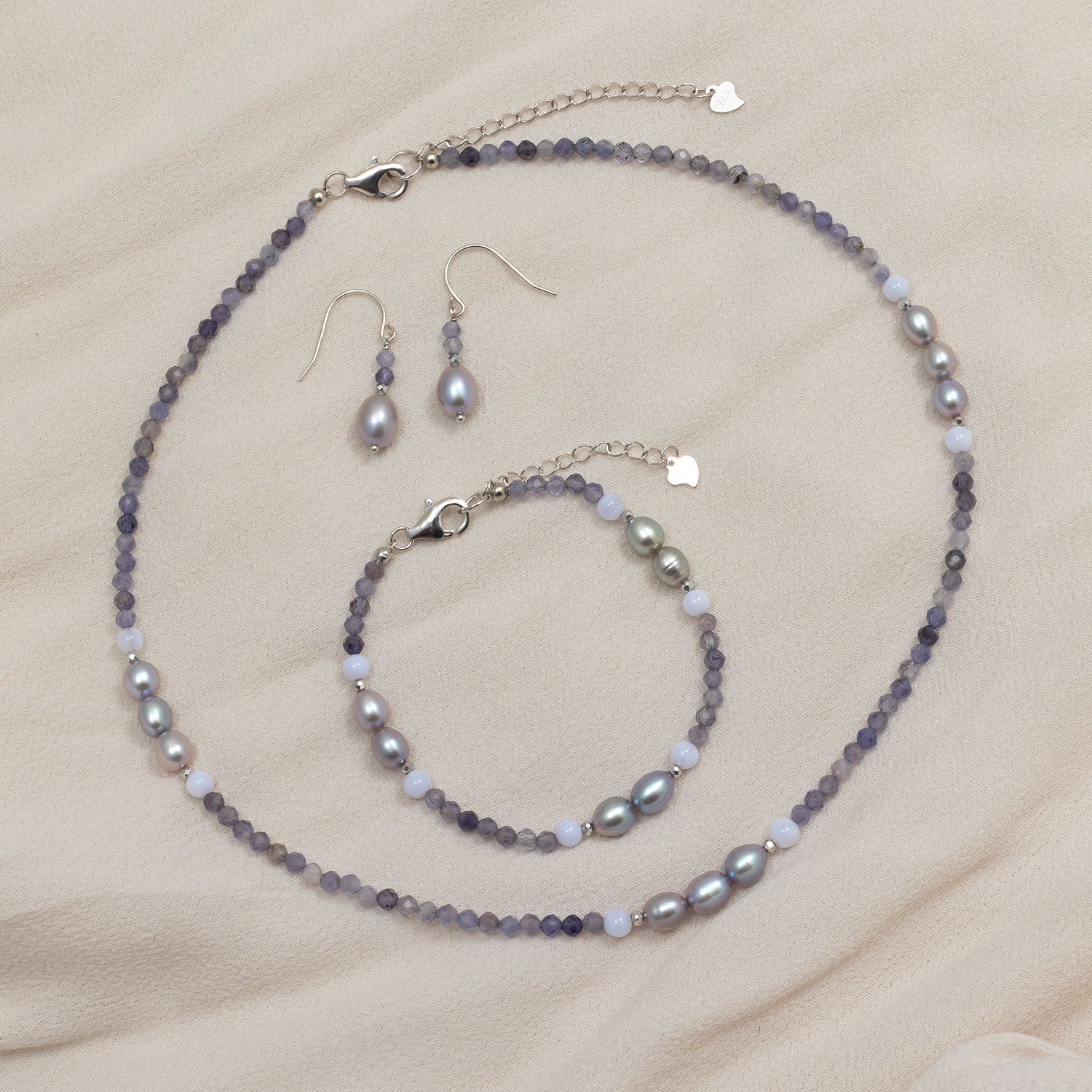 Delicate sterling silver drop earrings showcasing luminous freshwater pearls paired with faceted iolite beads, designed with a contemporary and elegant aesthetic.