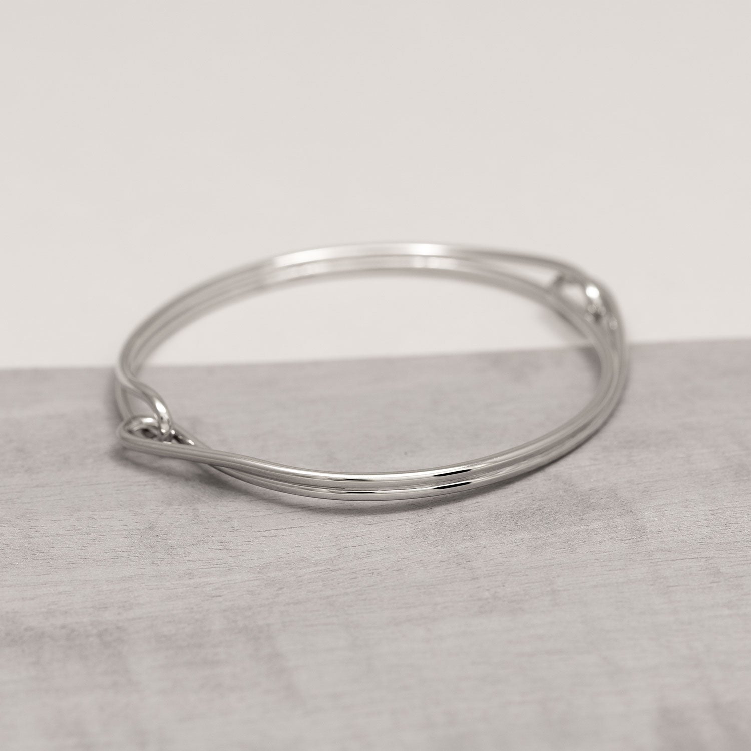 Sterling silver bangle featuring a fluid, looping circle design with a smooth, polished finish, reflecting elegant contemporary style in fine silver jewellery.