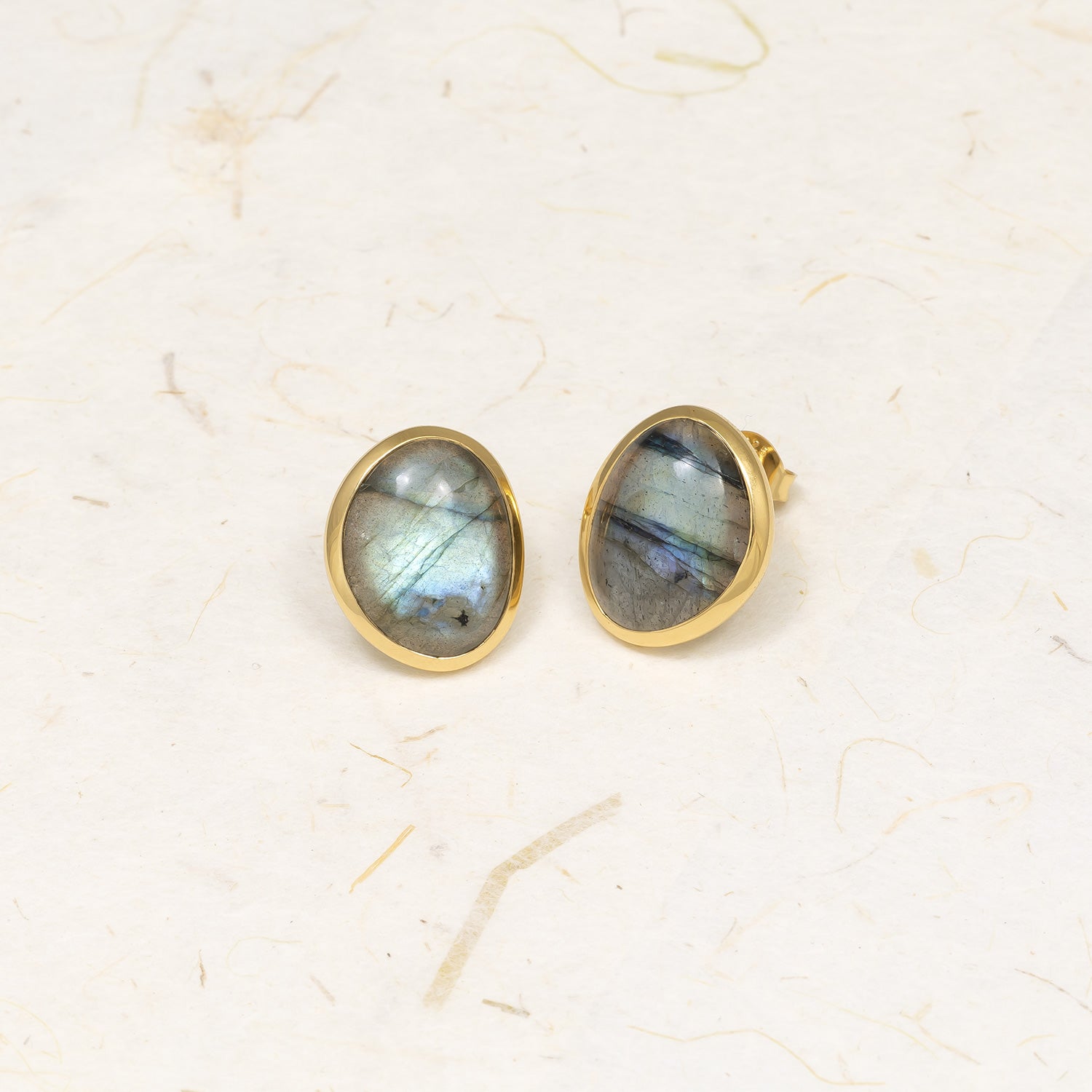 Oval-shaped gold vermeil stud earrings featuring iridescent spectrolite gemstones, showcasing a unique and refined design by an award-winning British jeweller.