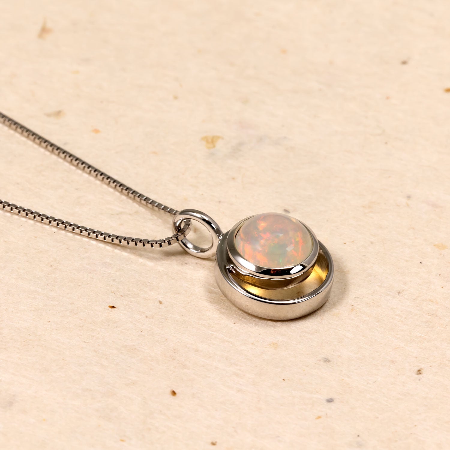 Polished sterling silver pendant with a luminous opal centerpiece, suspended from a sleek chain for a modern and elegant silver jewellery statement.