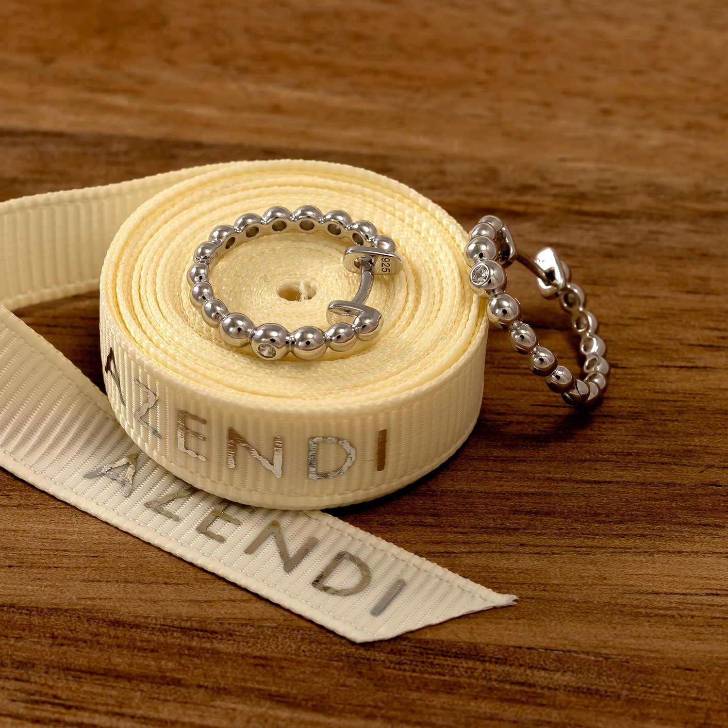 Pair of sterling silver hoop earrings designed with graduated bead detailing and sparkling cubic zirconia accents, displayed alongside a branded fabric ribbon.