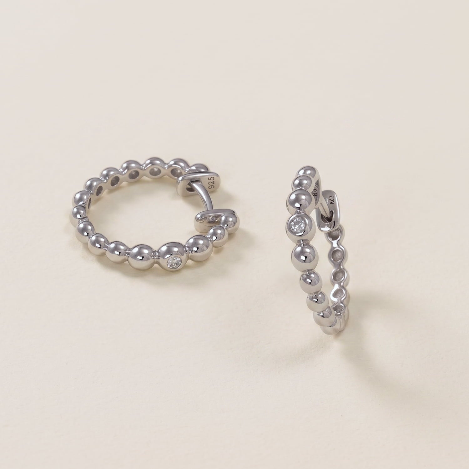 Pair of sterling silver hoop earrings featuring graduated bead detailing and small cubic zirconia accents.