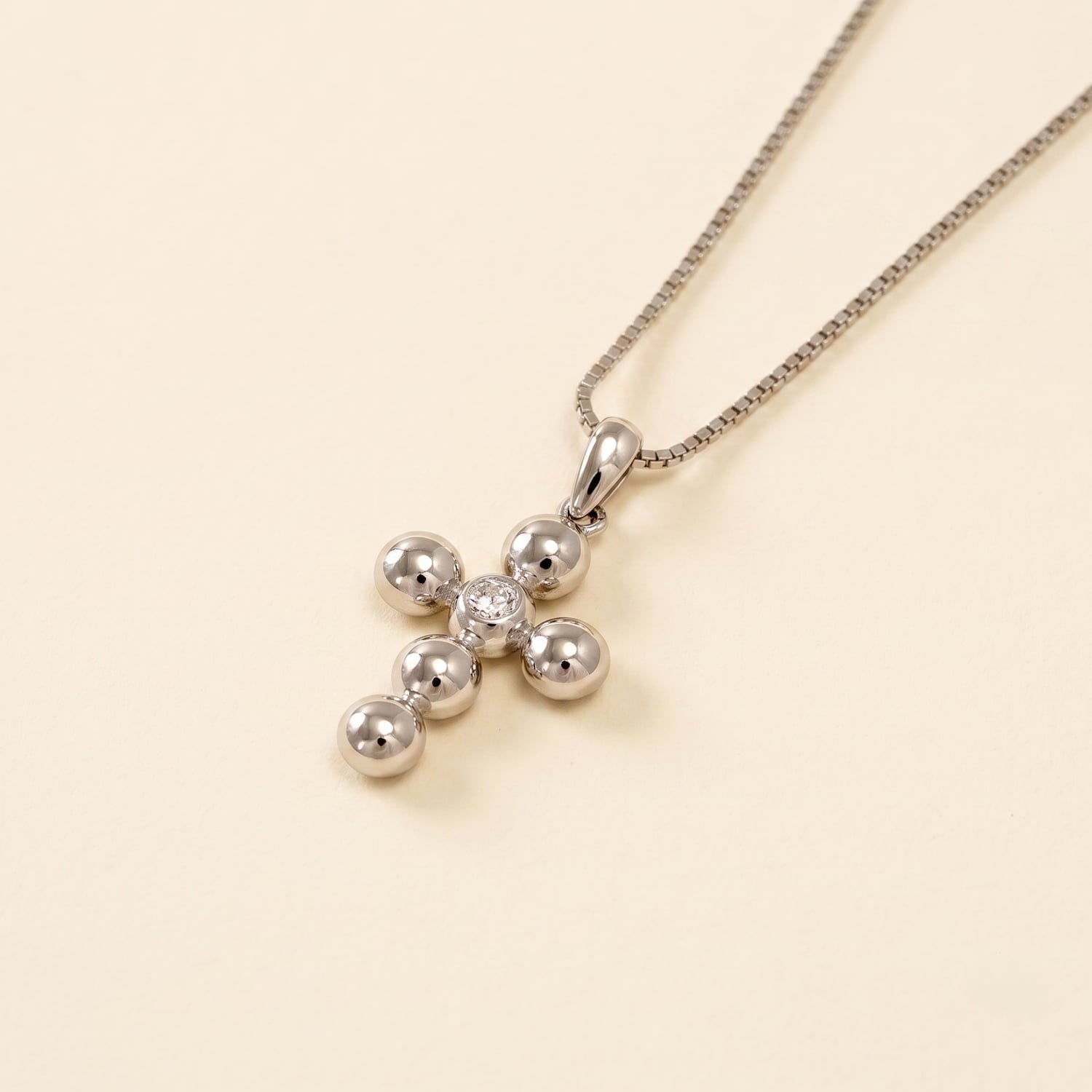 Sterling silver pendant shaped as a beaded cross featuring a central cubic zirconia, suspended on a fine chain, reflecting refined British craftsmanship.