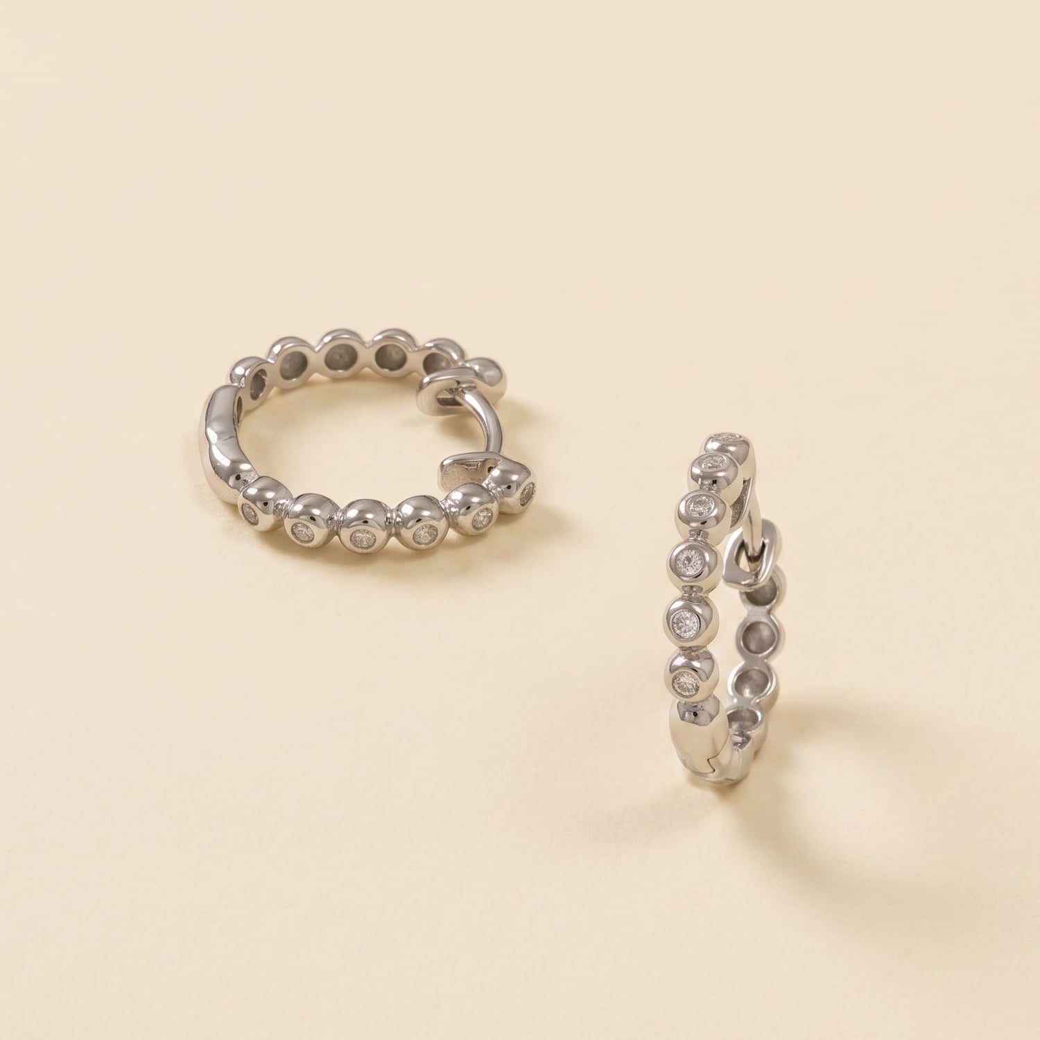 Pair of sterling silver hoop earrings featuring a row of polished beads accented with sparkling cubic zirconia stones, exemplifying contemporary British craftsmanship.