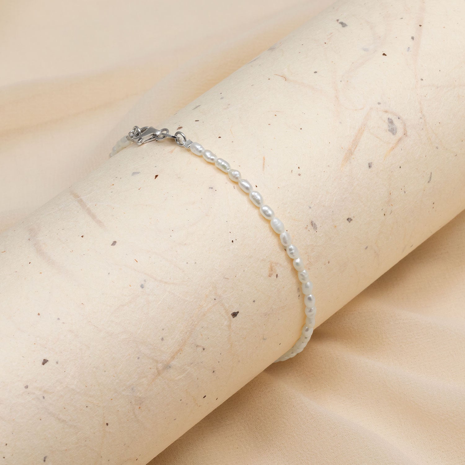 Delicate sterling silver bracelet adorned with freshwater seed pearls, featuring a fine chain and subtle clasp, embodying refined British silver jewellery design.