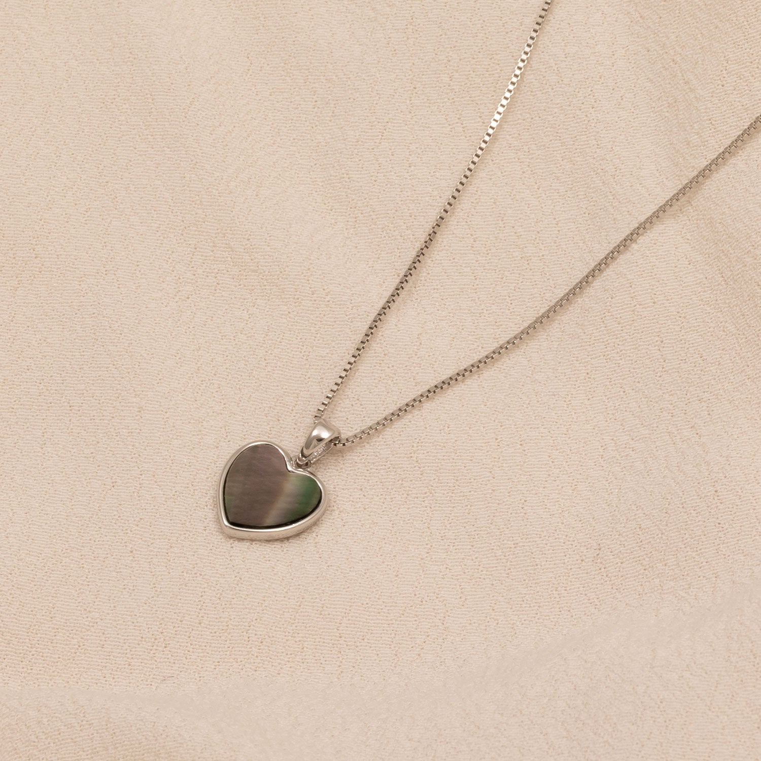 Delicate sterling silver necklace featuring a sculptural heart pendant in grey mother of pearl, showcasing expert design and contemporary British silver jewellery craftsmanship.