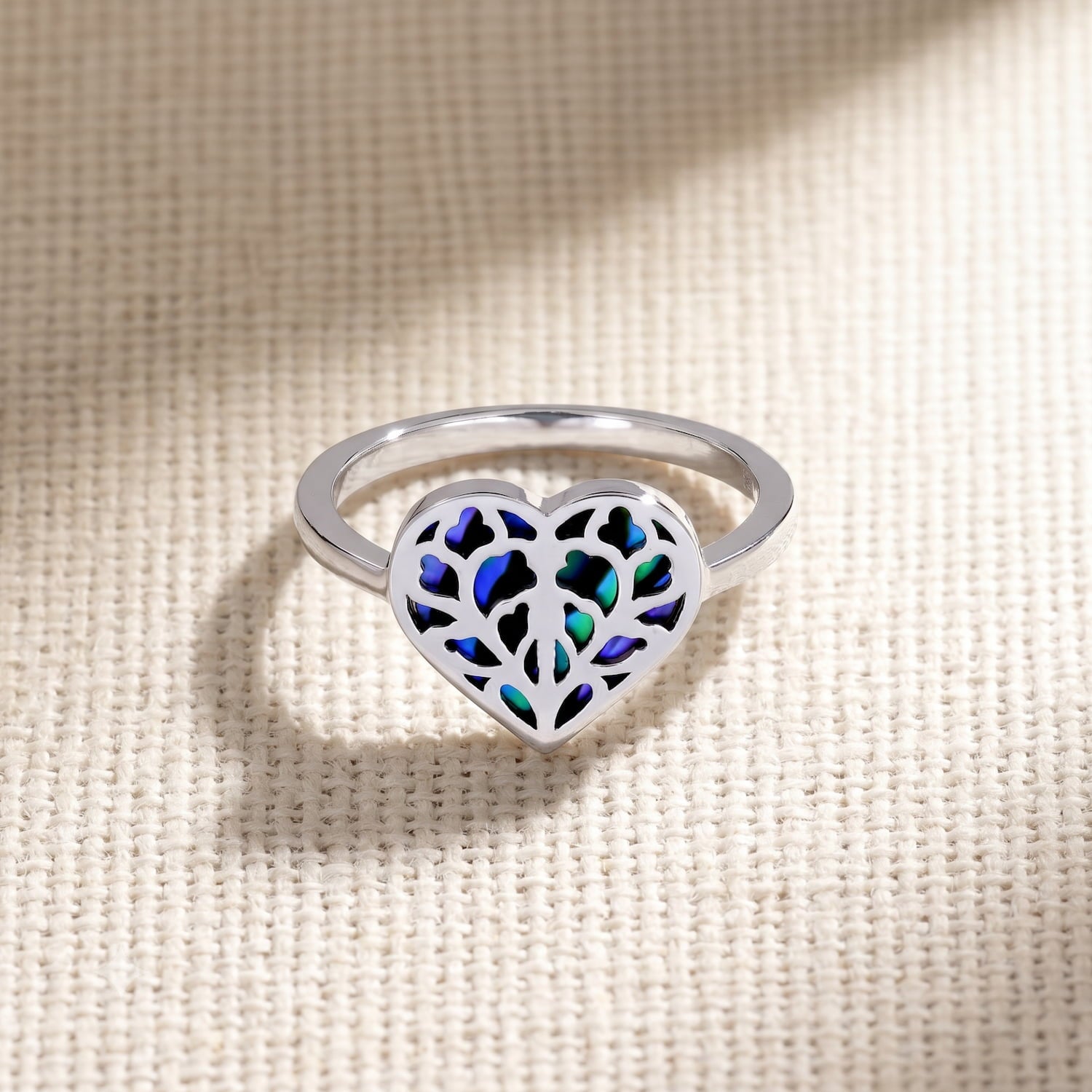 Sterling silver ring featuring a sculptural openwork heart design with iridescent abalone inlay, combining contemporary craftsmanship and elegant silver jewellery style.