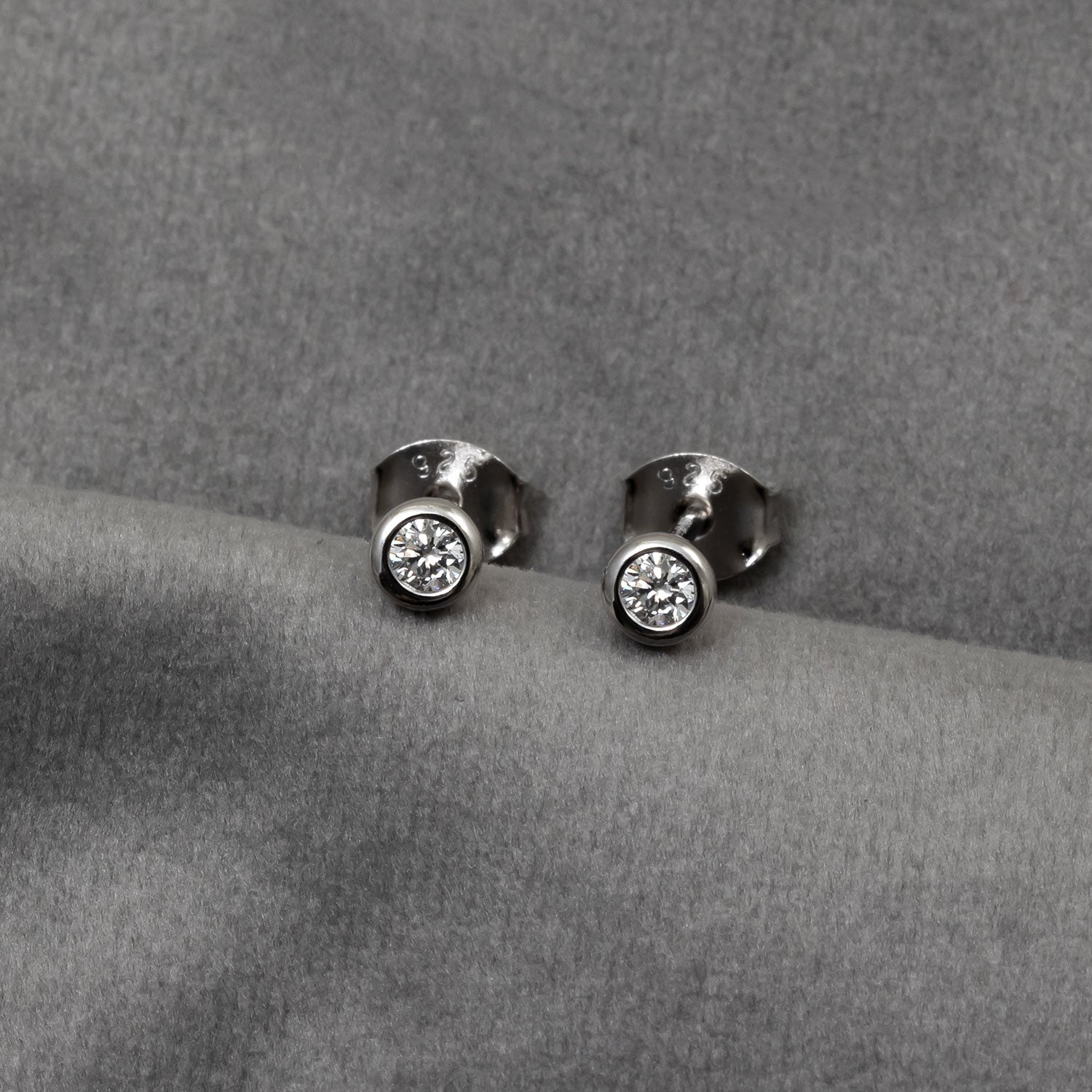 Pair of sterling silver solitaire stud earrings each set with a single 0.15 carat lab grown diamond in a smooth bezel setting for a refined, timeless look.