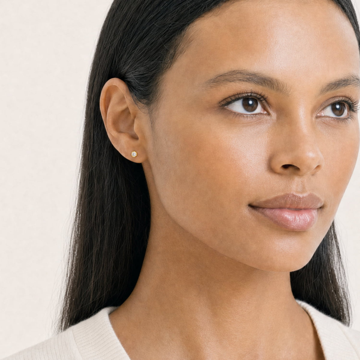 Model wears a pair of gold vermeil stud earrings featuring solitaire 0.15 carat lab grown diamonds set in polished round bezels, showcasing a classic and refined design.